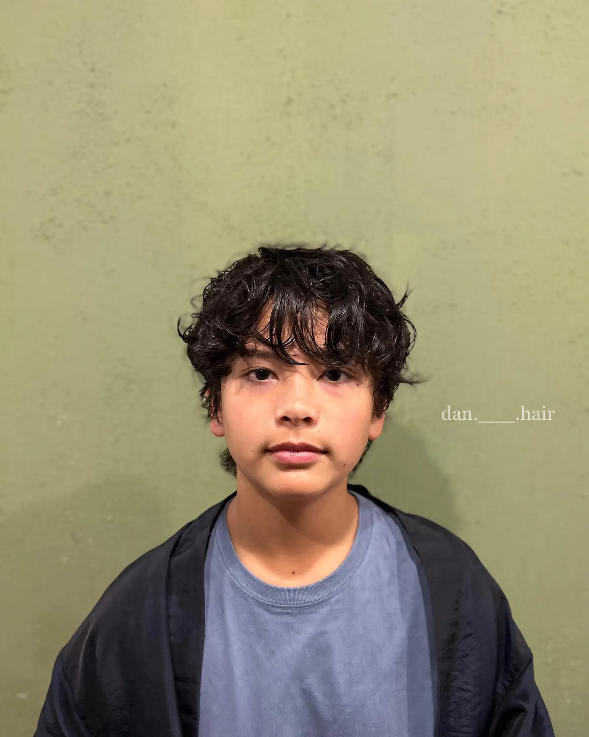 A textured short perm with loose, tousled waves and piecey bangs framing the forehead. 1
