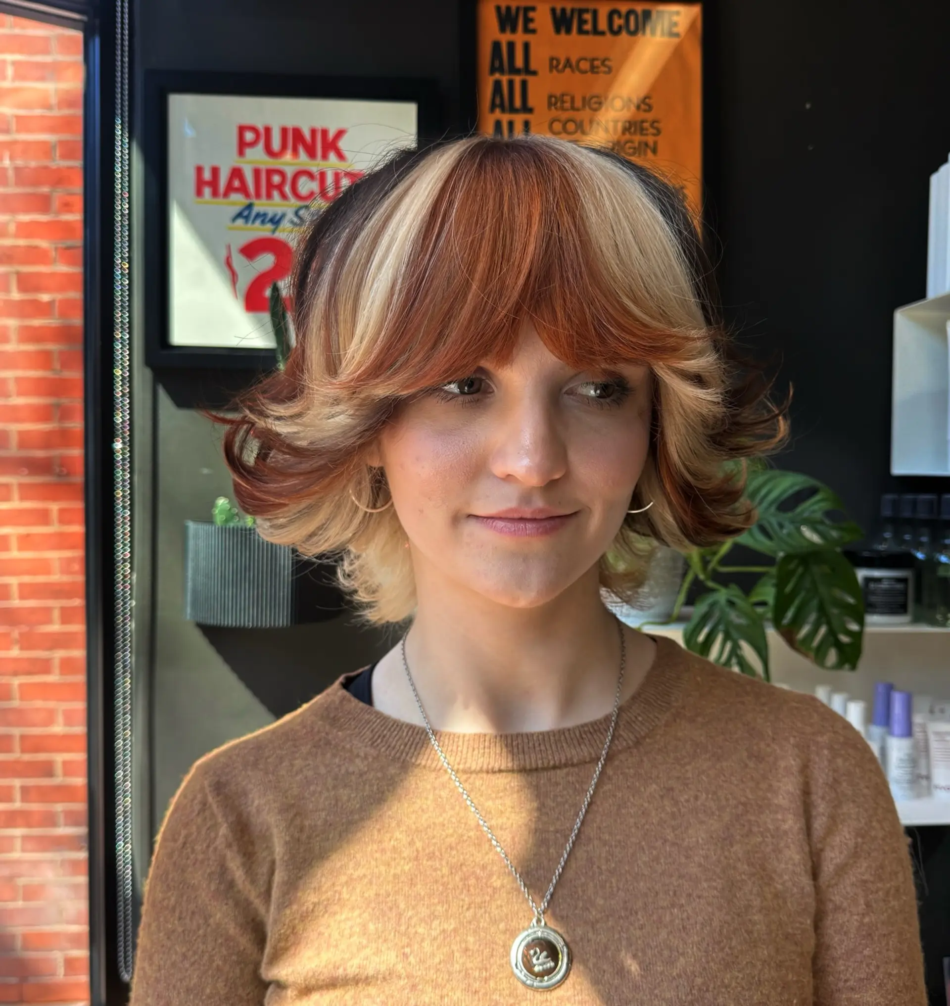 A retro 70s-inspired feathered shag bob featuring dramatic winged bangs and flipped-out ends. The look is accentuated with a high-contrast calico color pattern blending warm copper, light blonde, and deep brunette tones. 1