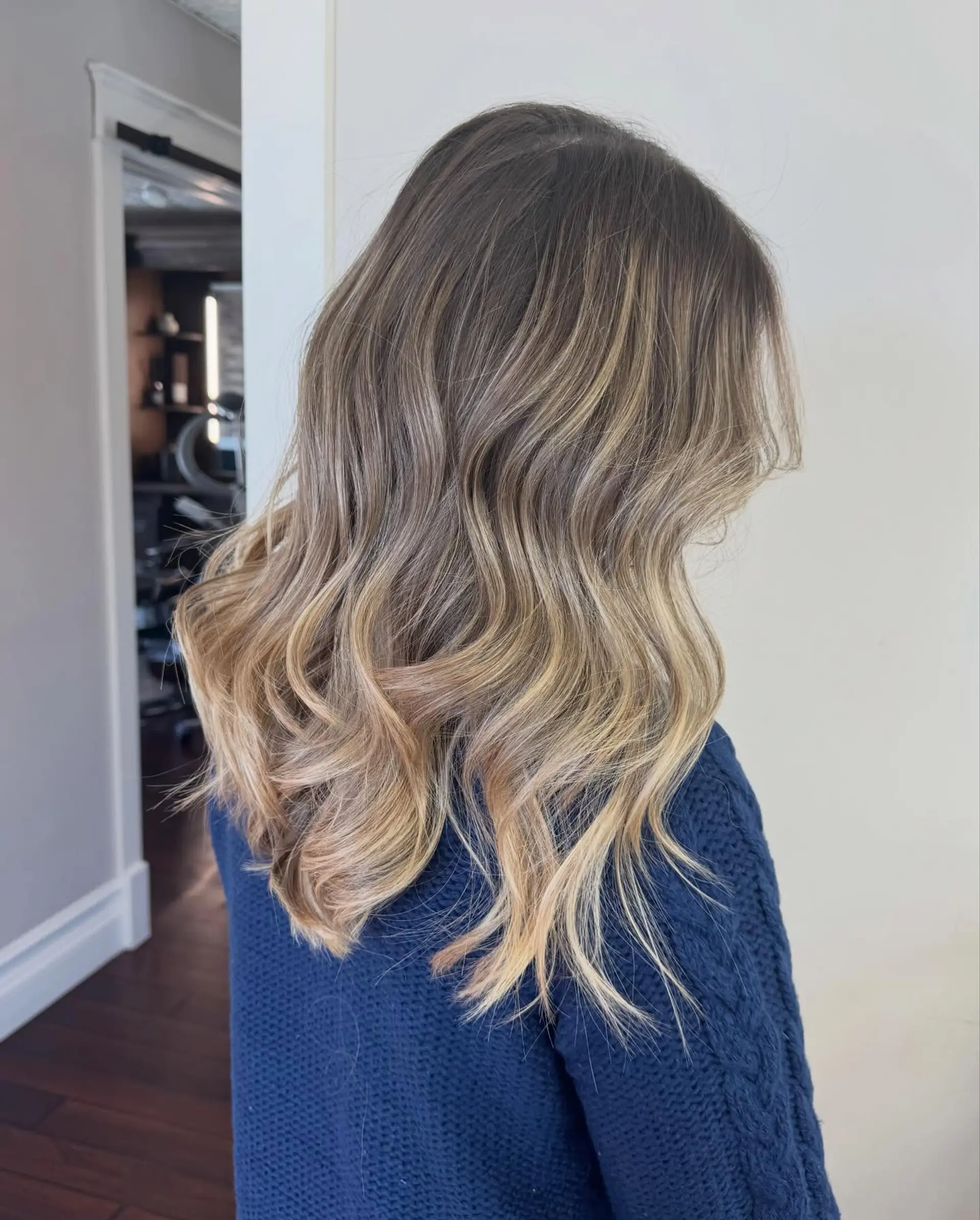 Long hair featuring a seamless blonde balayage transition from a natural brown base into bright blonde ends, finished with soft barrel waves. 1