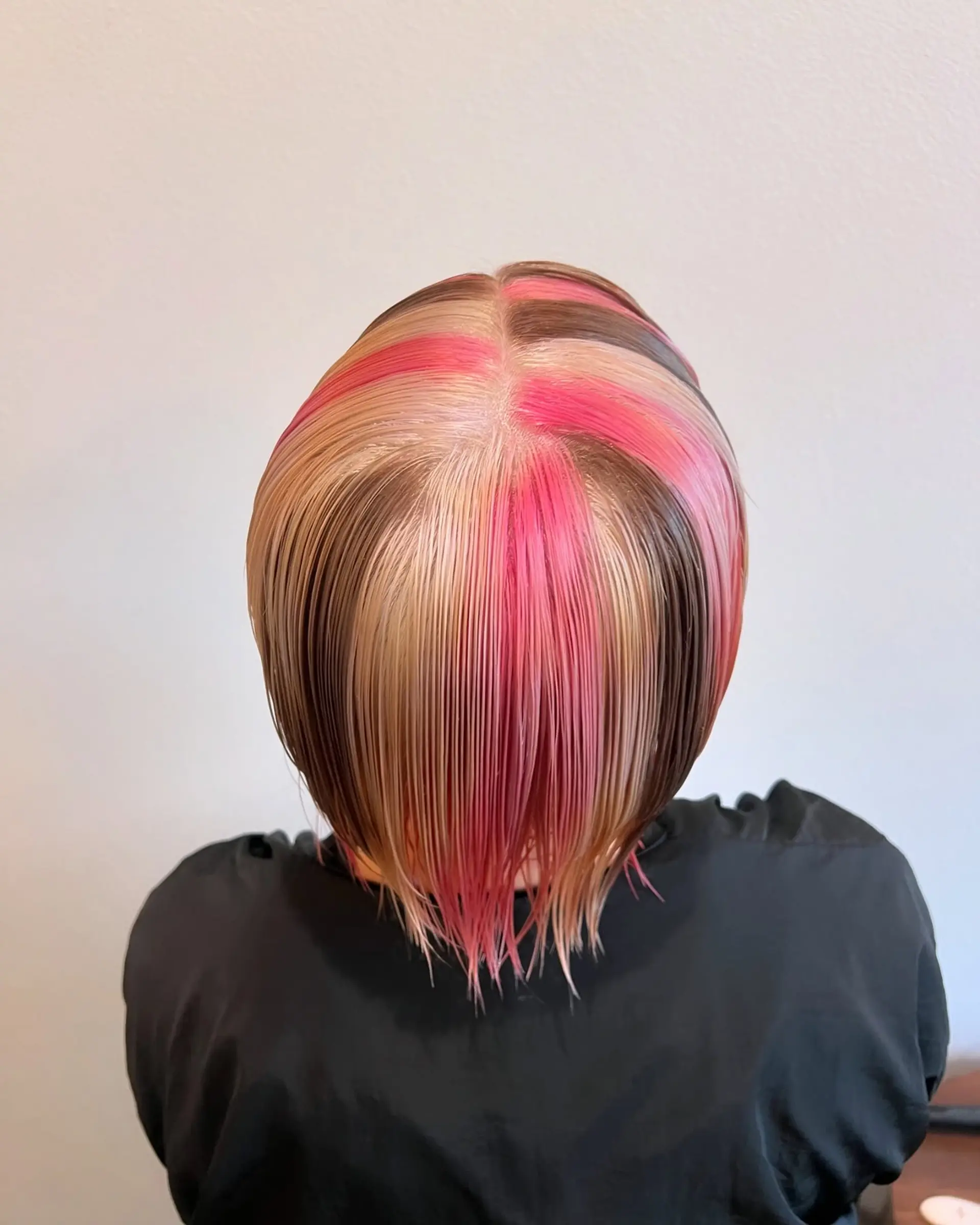 This bold pixie bob features a multi-tonal color block design, incorporating vivid and pastel pinks, light blonde, and a dark brown section for a striking contrast. The cut is layered, ending above the nape, and styled with a blunt fringe. 4