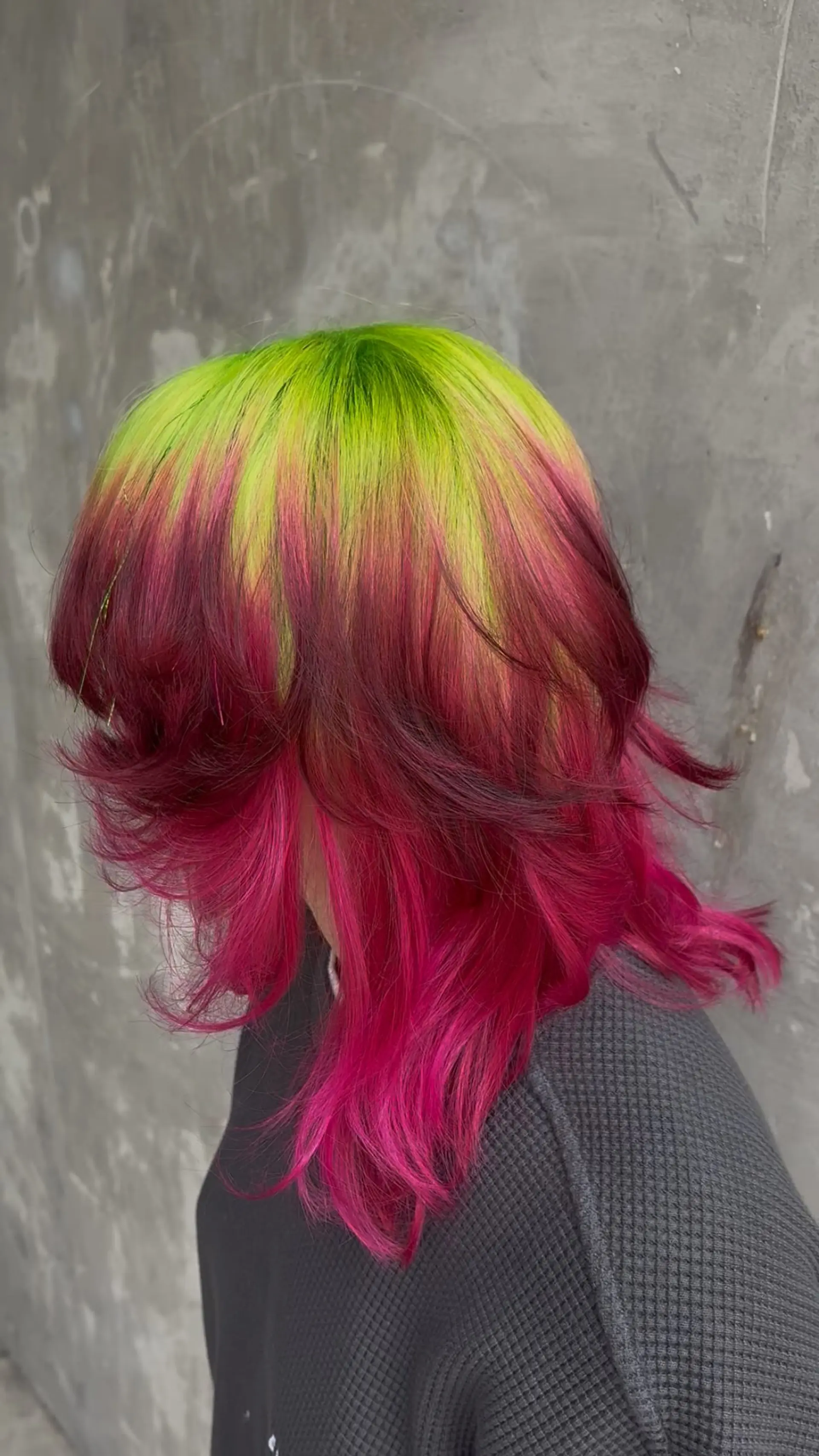 A medium-length textured shag featuring vibrant neon green ghost roots blending into bold magenta and bright pink ends. 1