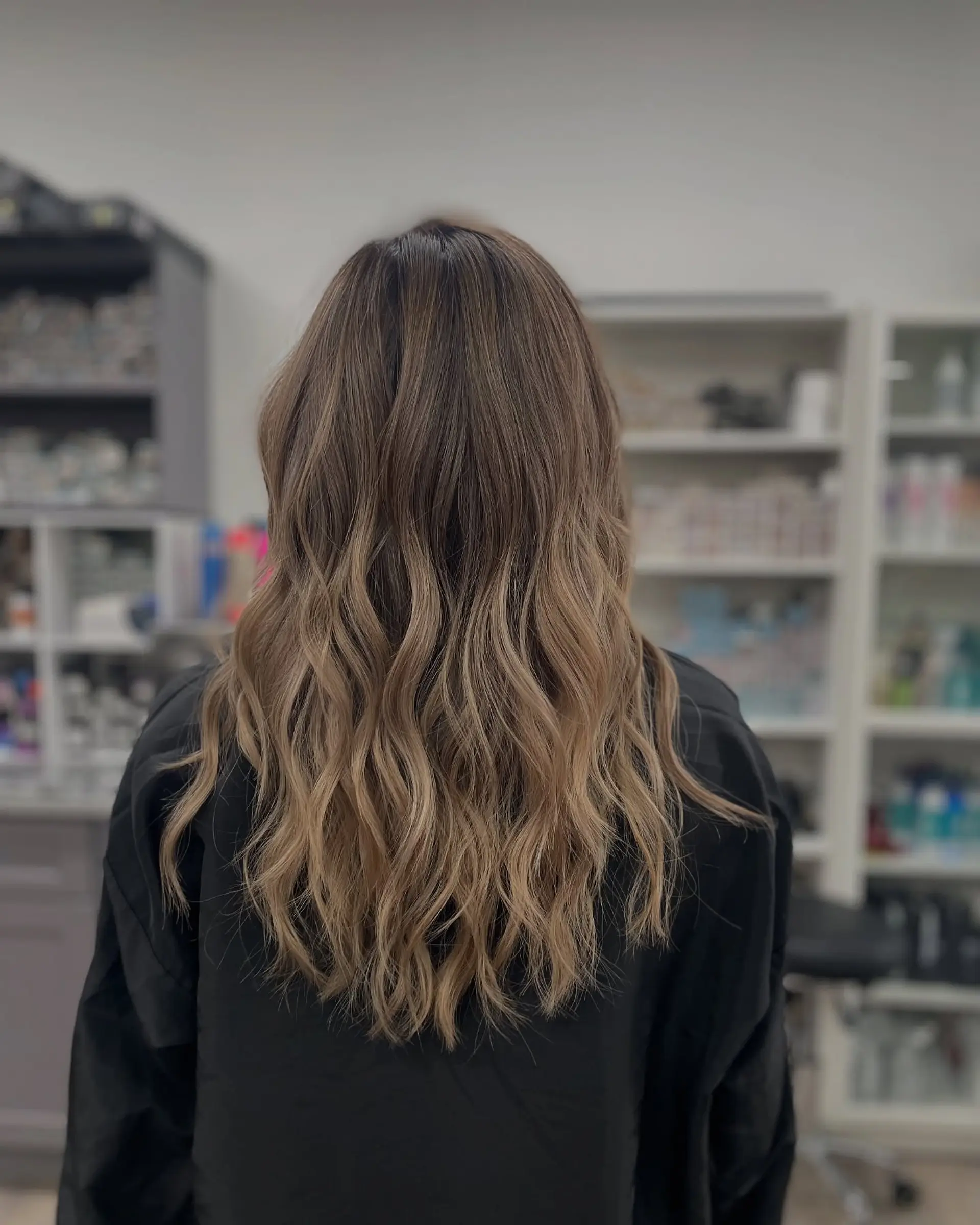Long, wavy hair with a balayage color melt from brown to blonde. 1