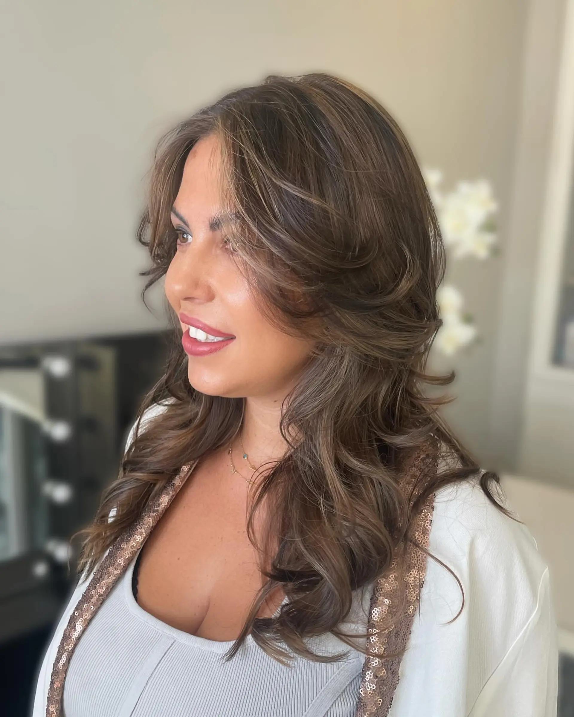 Long dimensional brunette hair styled in a voluminous blowout with sweeping face-framing layers. 1