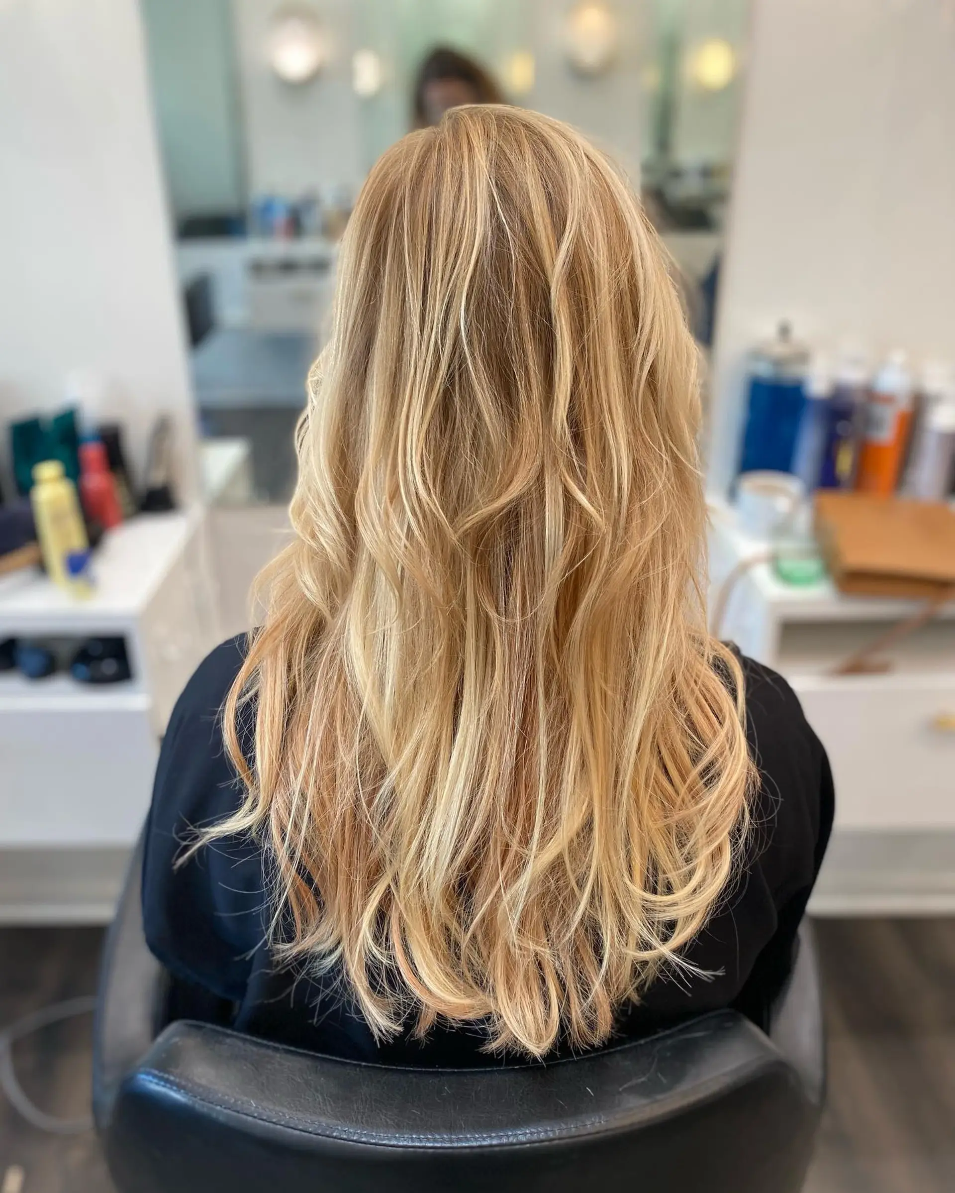 Long multi-tonal blonde hair with layers, styled into soft textured waves. 1