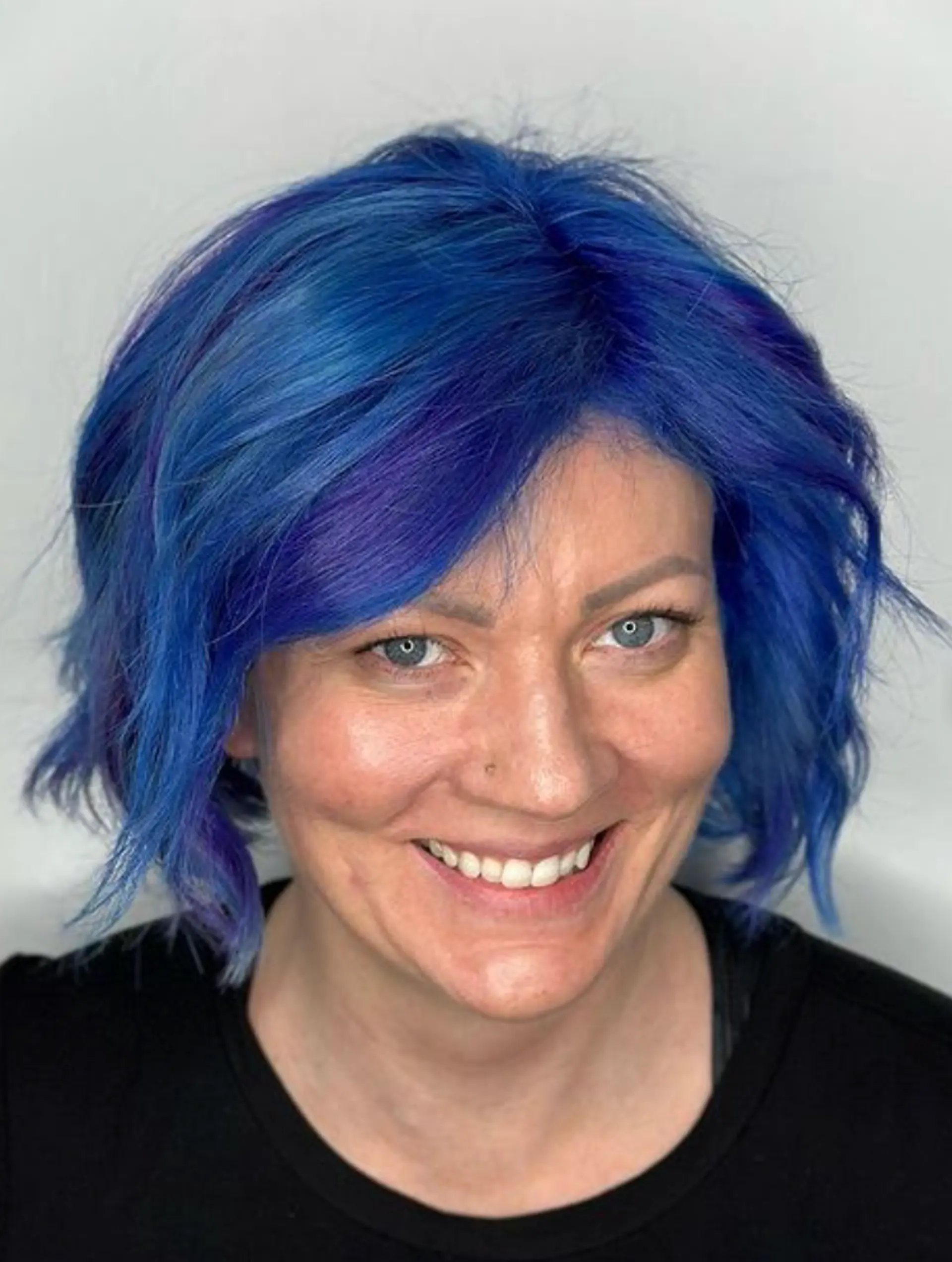 A short, wavy bob with vivid blue and indigo tones, featuring textured layers, a side-swept fringe, and tousled waves for a lively, youthful appearance.

Color by @simabeautynyc
Cut and style by @juliamannino_hair
 2