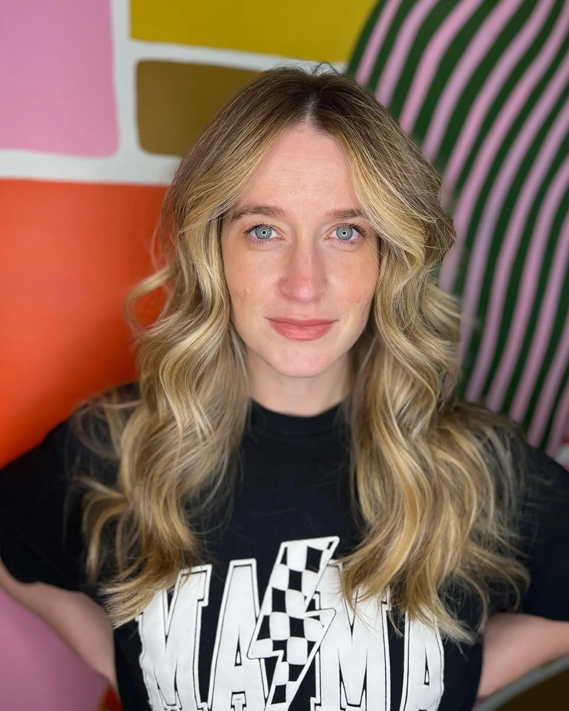 Long dimensional golden blonde balayage styled with soft, voluminous waves and face-framing curtain layers. 1