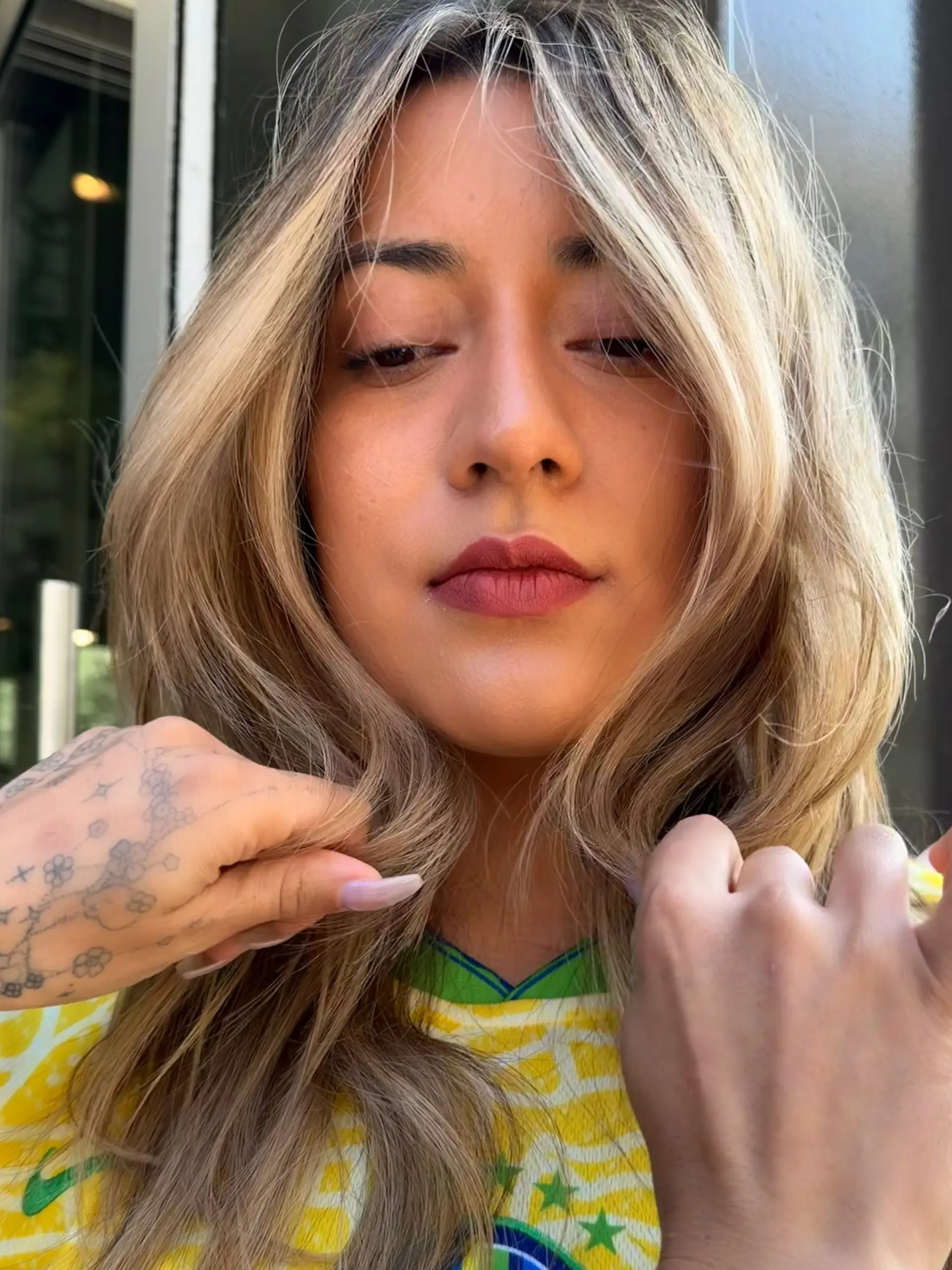 Medium-length beige blonde balayage styled with soft textured waves and face-framing curtain layers. 1