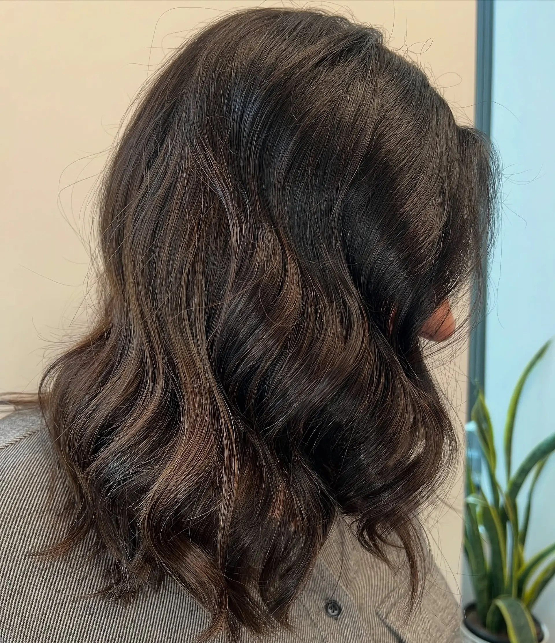 Shoulder-length rich dark brunette hair styled into loose, glossy waves. 1