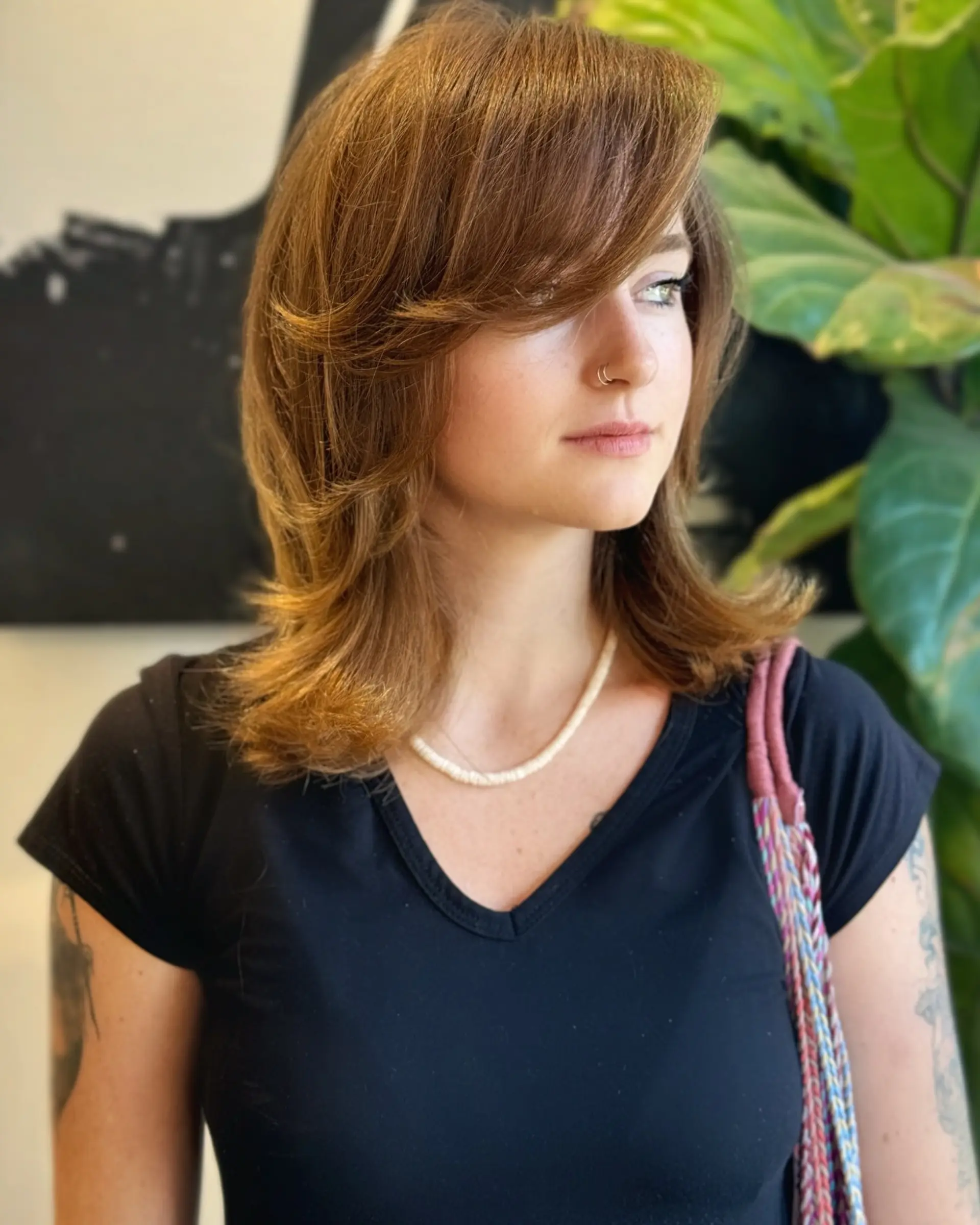 A voluminous 90s-inspired layered cut with feathered face framing, side-swept bangs, and flipped ends in warm light brown. 1