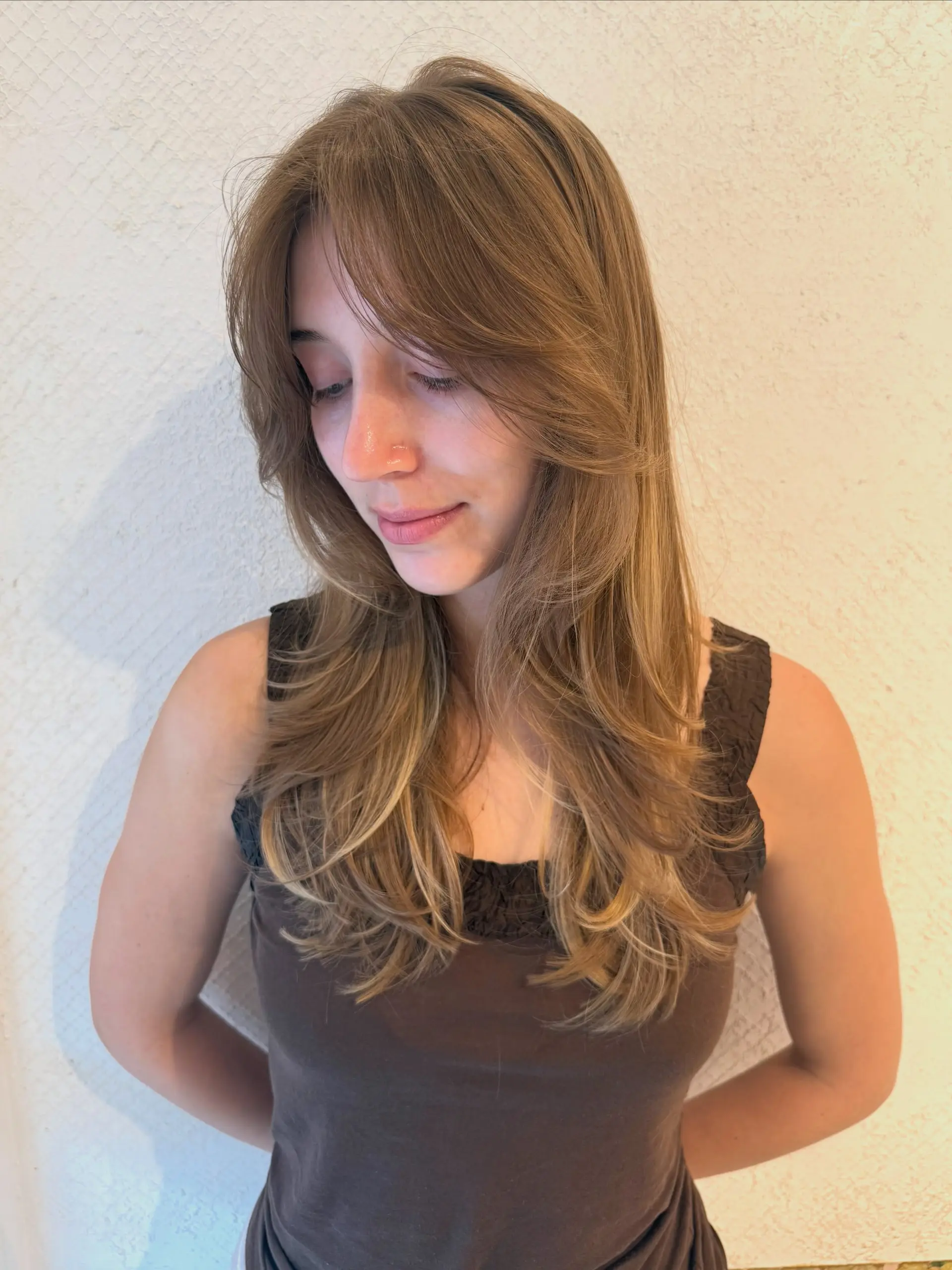 A long, smooth layered haircut featuring soft curtain bangs and blended face-framing layers curled gently at the ends. 1