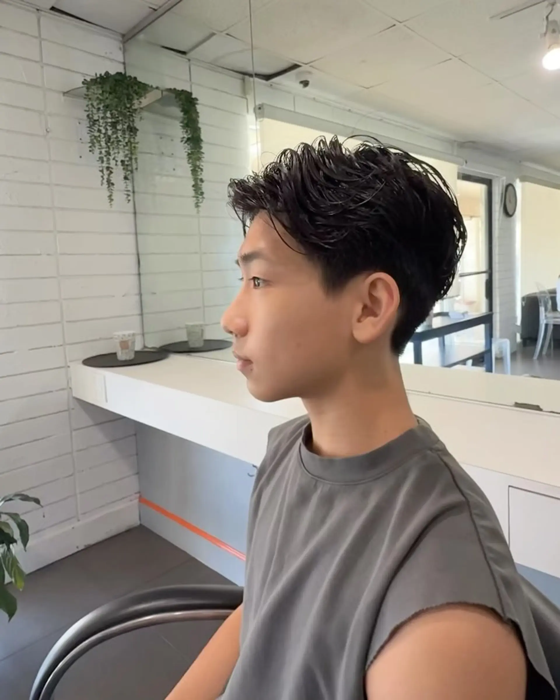 A short cut styled with a soft perm, featuring natural waves and subtle texture on top with neatly tapered sides. 1