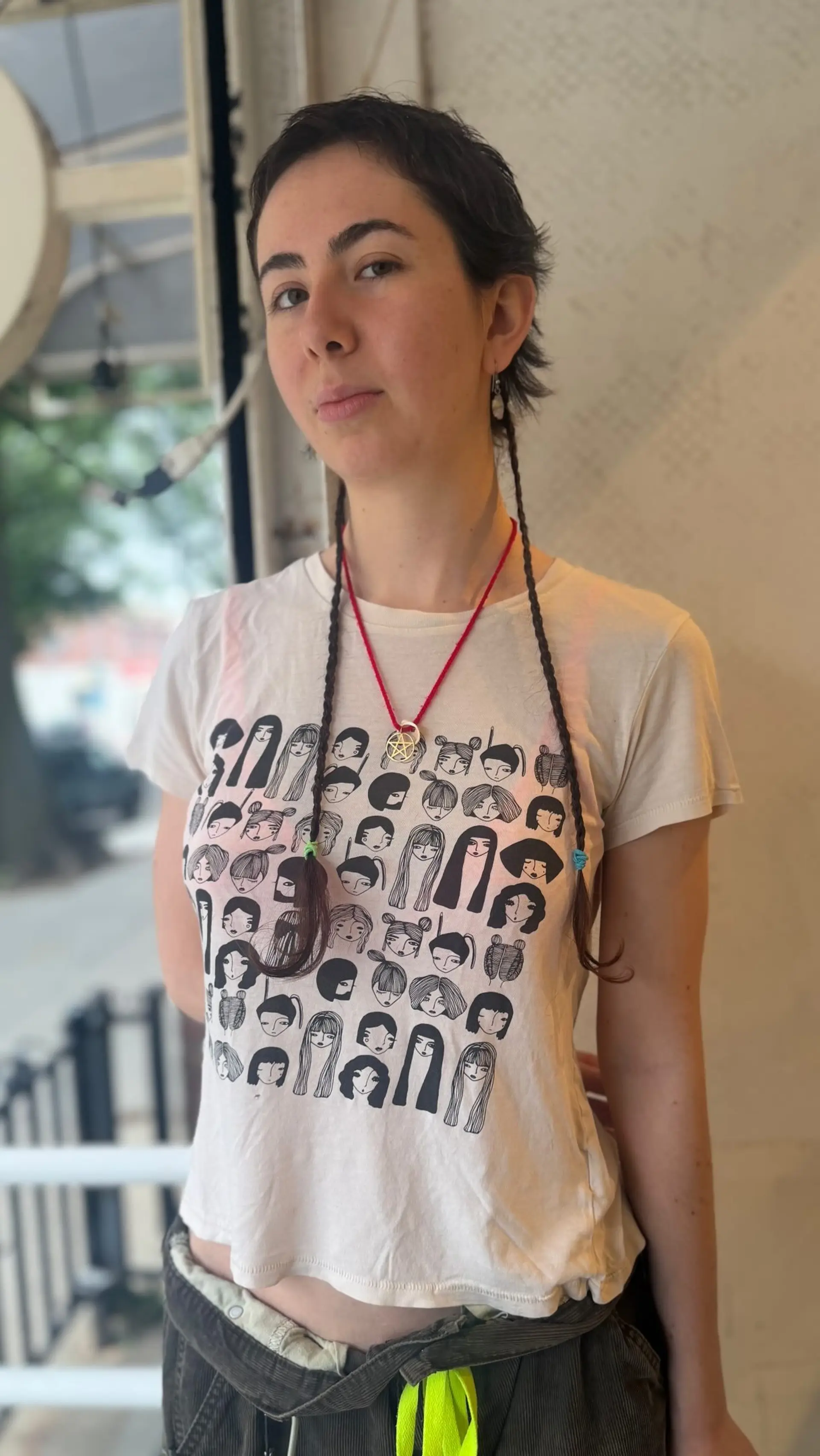 A textured, choppy pixie haircut featuring soft micro bangs and two long, thin braids draping down the front. 1