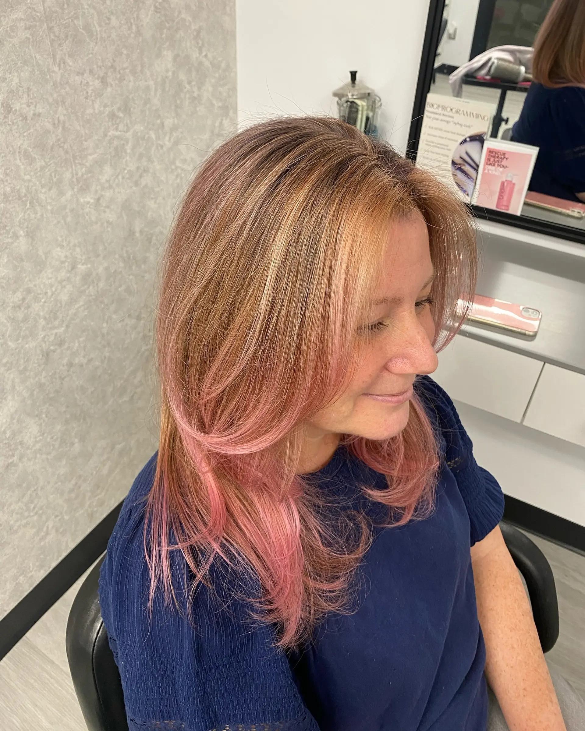 Medium-length layered hairstyle featuring warm blonde highlights seamlessly blending into soft pastel pink and rose-toned ends, styled in a sleek blowout with gently curved tips. 1