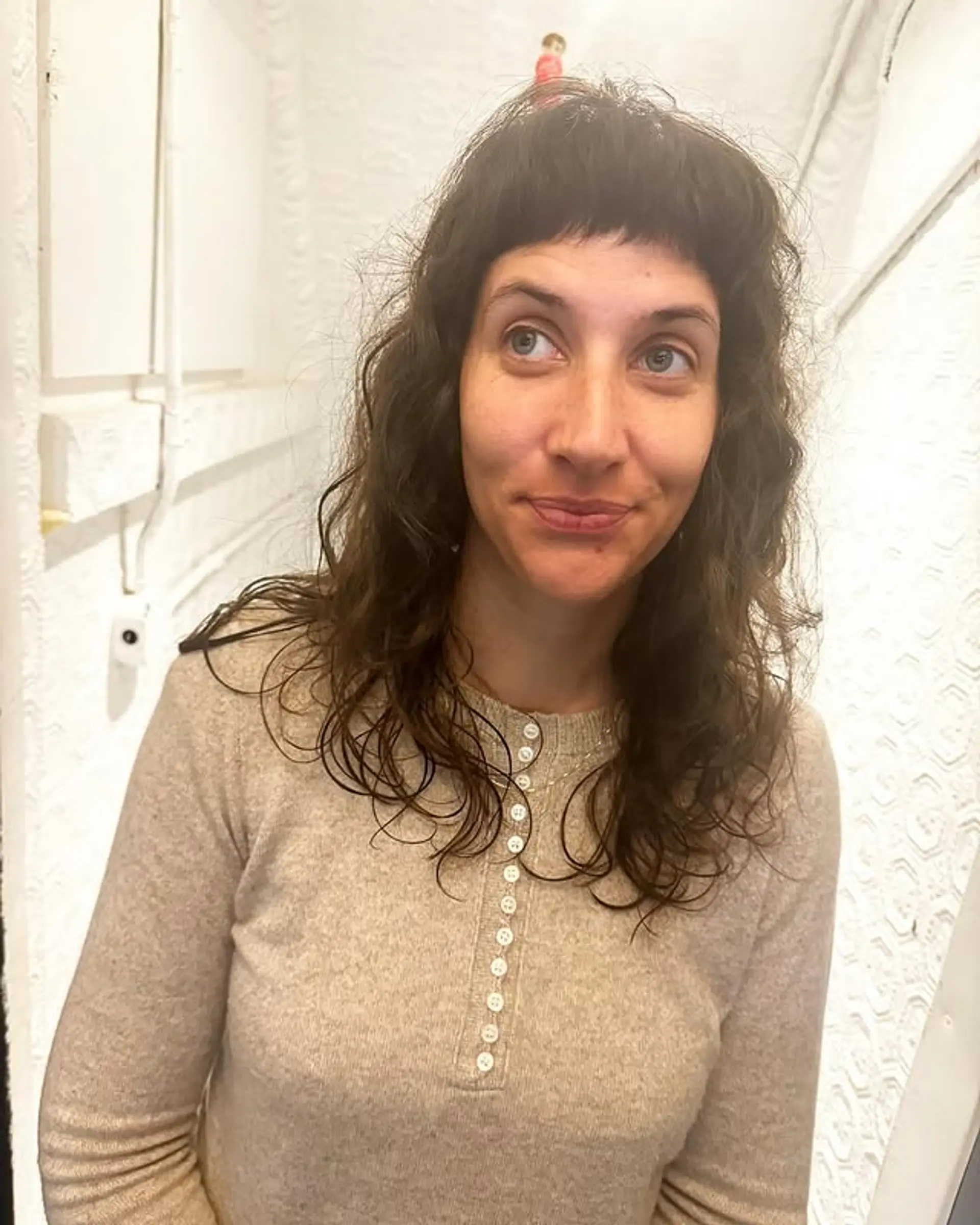 A wavy shag haircut with short, blunt baby bangs and lots of layers. 1