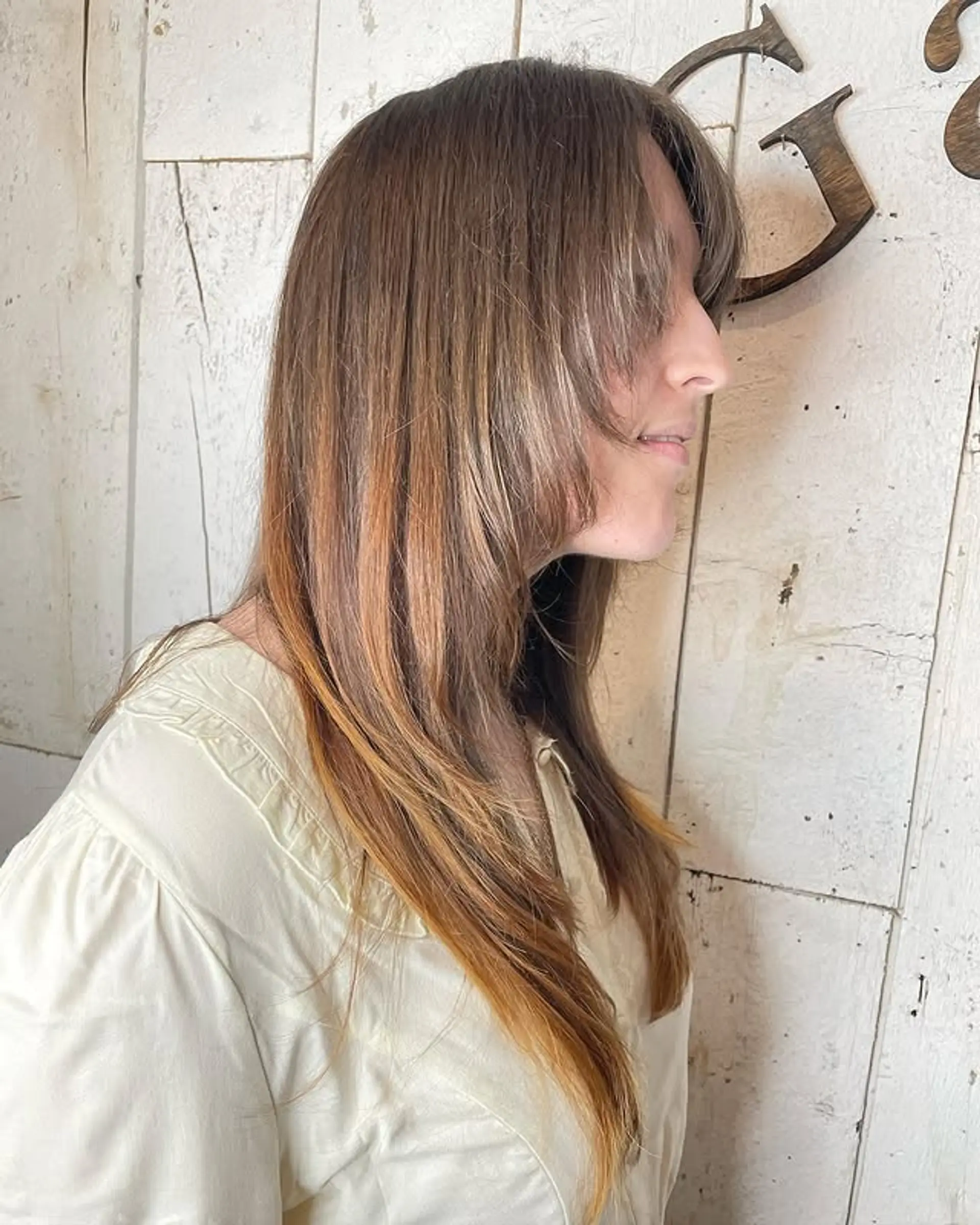 A layered medium-length hairstyle with face-framing layers and wispy bangs. 1