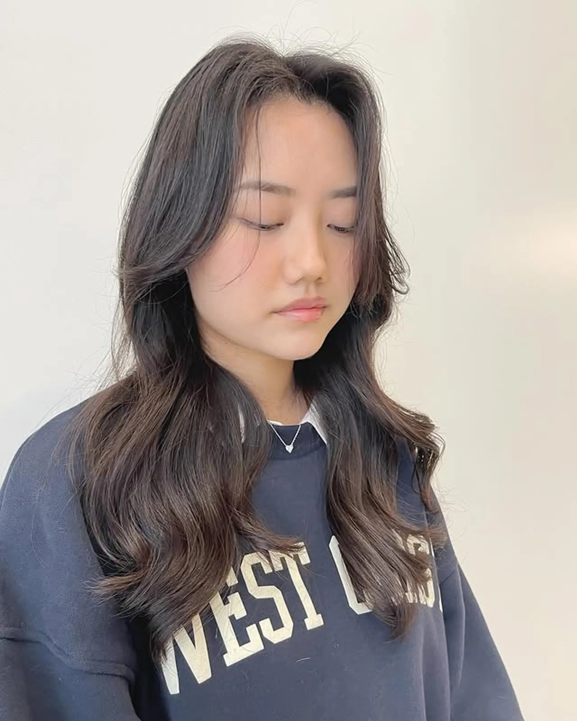 A layered haircut with curtain bangs and soft waves. 1