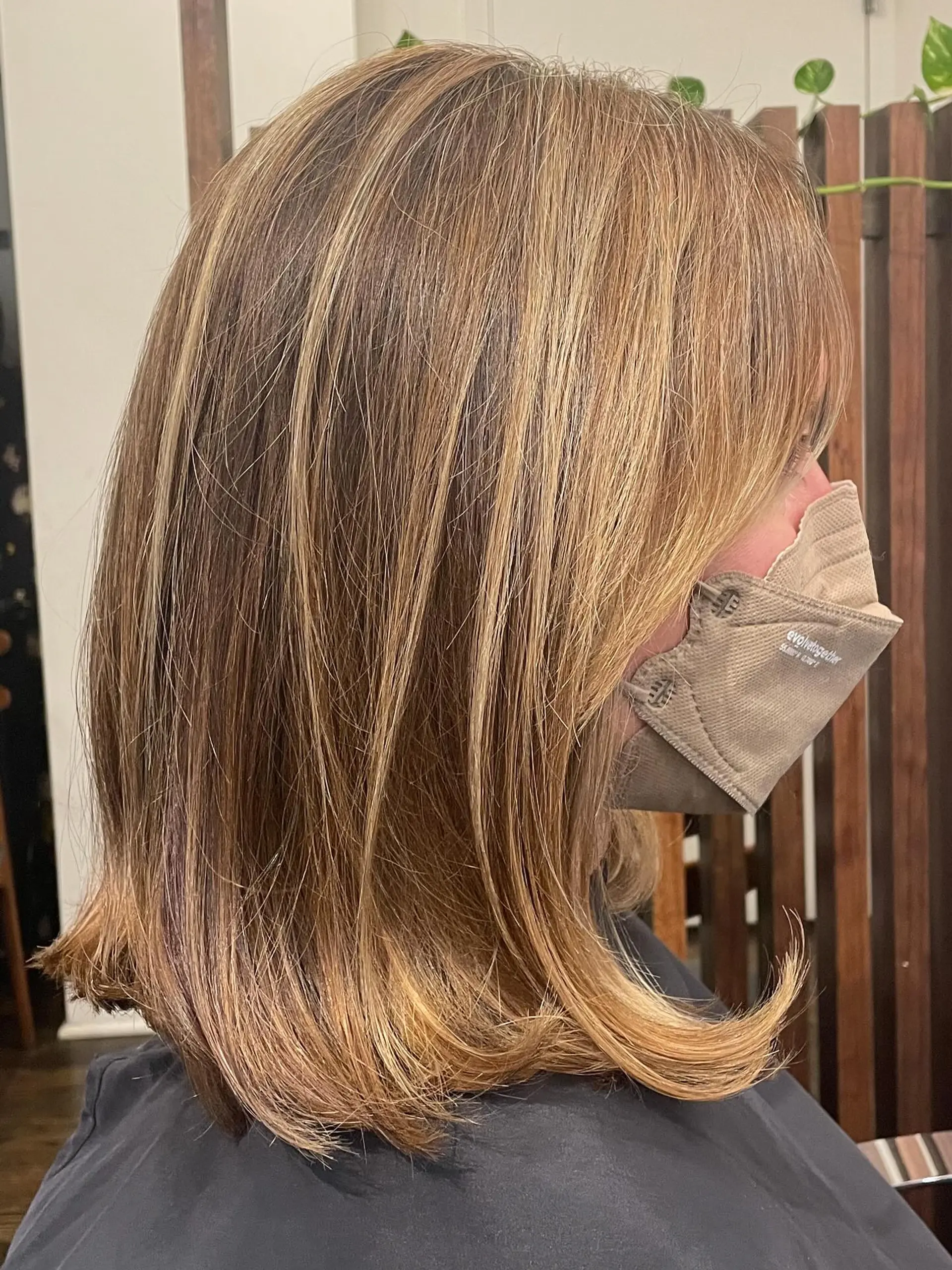 A textured shoulder-length lob featuring warm caramel bronde highlights with softly flipped ends. 1