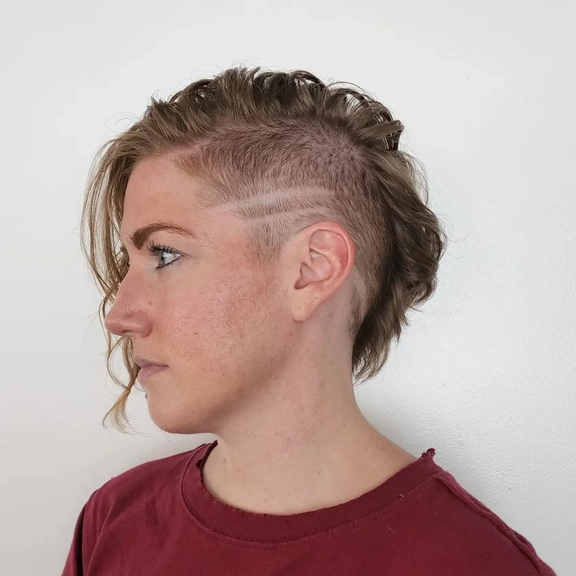 Daring combination of shaved sides with two line designs and longer wavy strands on top for a bold, modern effect. 1