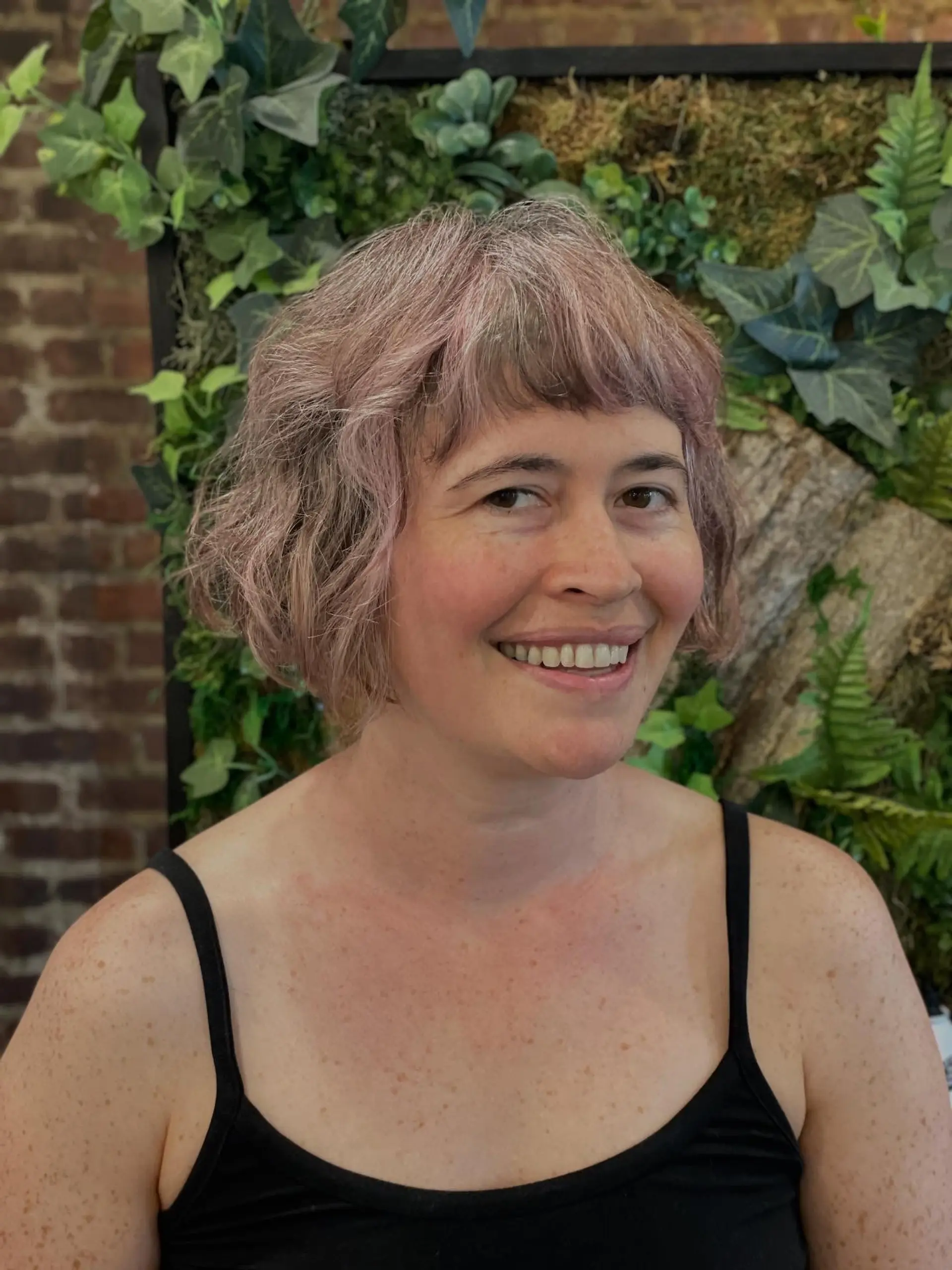 A wavy, textured jaw-length bob featuring short fringe bangs and a pastel blend of silver and soft pink tones. Current Cut My Hair service: $215 for haircut and included finish only; displayed color is not included. 1