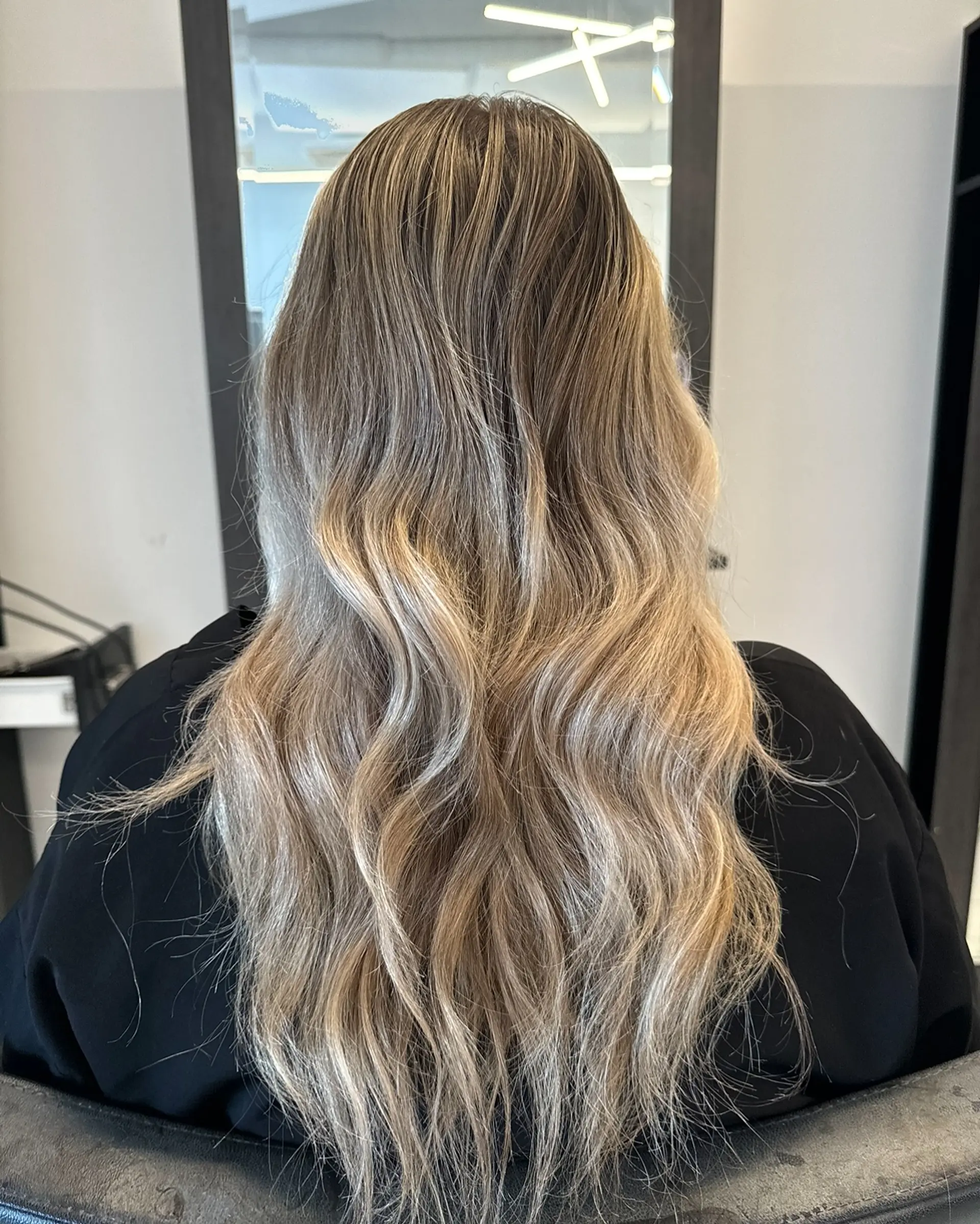 Long, dimensional ash blonde hair styled into soft, cascading waves. 1