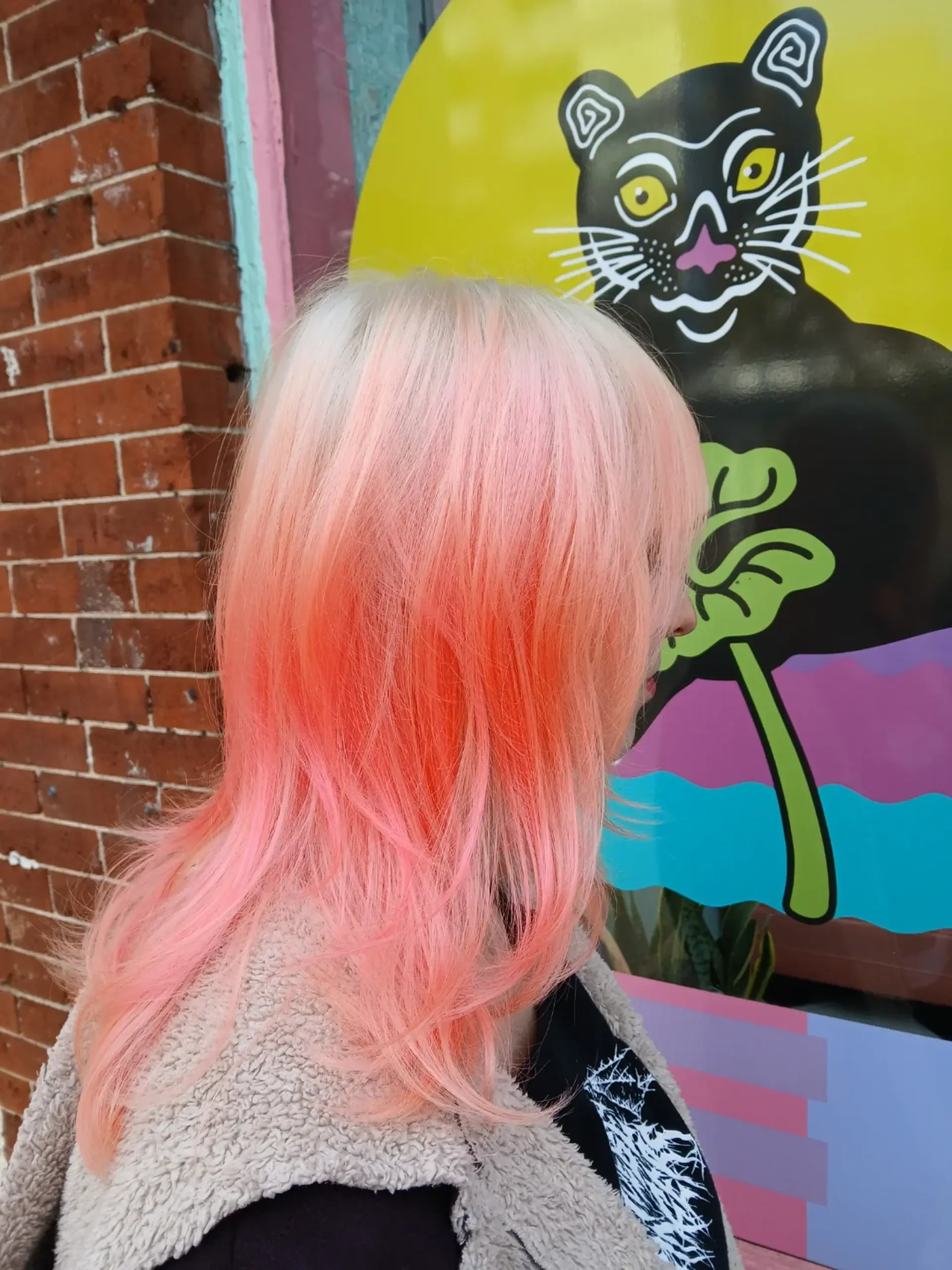Medium-length layered cut styled with soft movement, featuring platinum blonde roots blending into vivid coral and pastel pink tones. 1