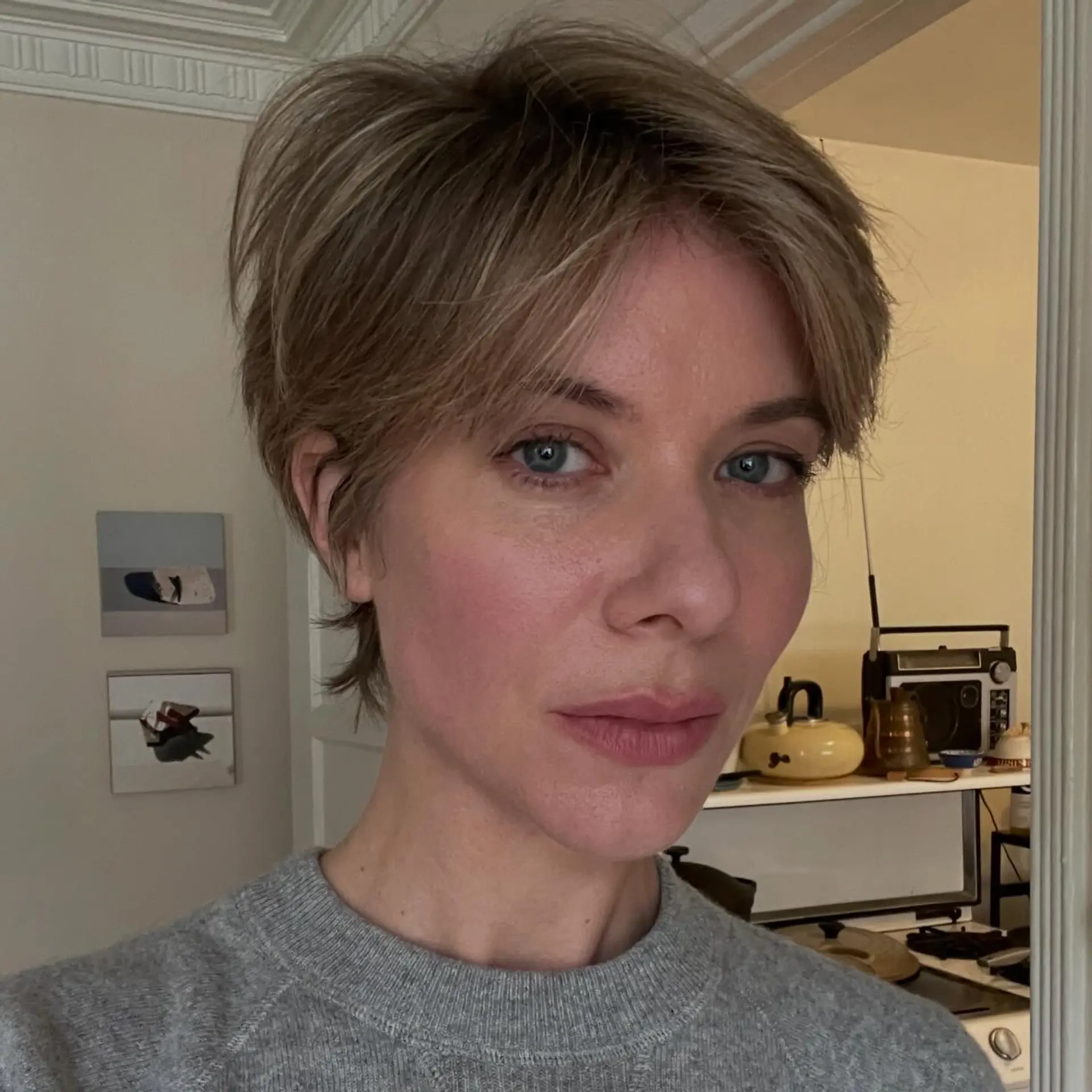 A textured short pixie cut with soft parted bangs, styled with subtle volume and dimension from natural gray blending highlights. 1