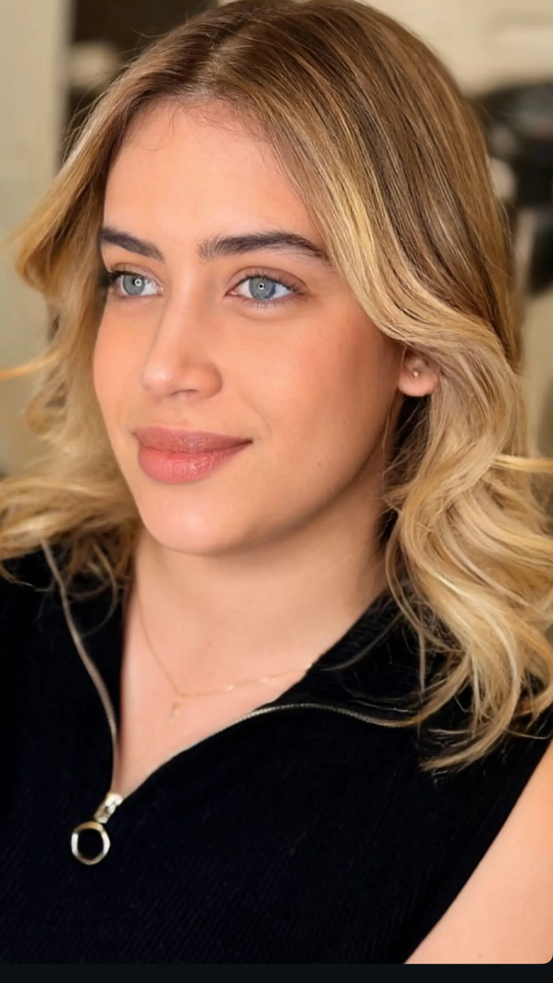 Medium-length blonde balayage styled with soft, face-framing waves and a polished blowout finish. 1