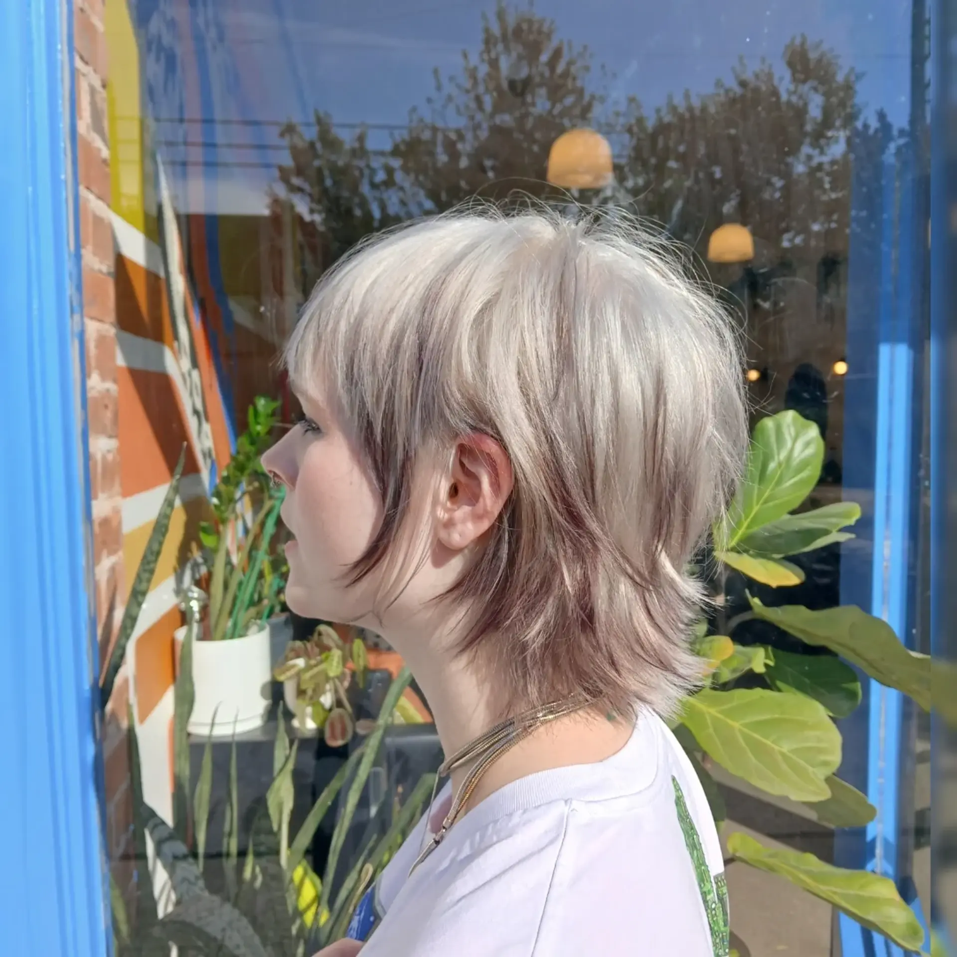 A textured short mullet shag cut with platinum ash blonde layers over dark, contrasting peekaboo underlayers. 1
