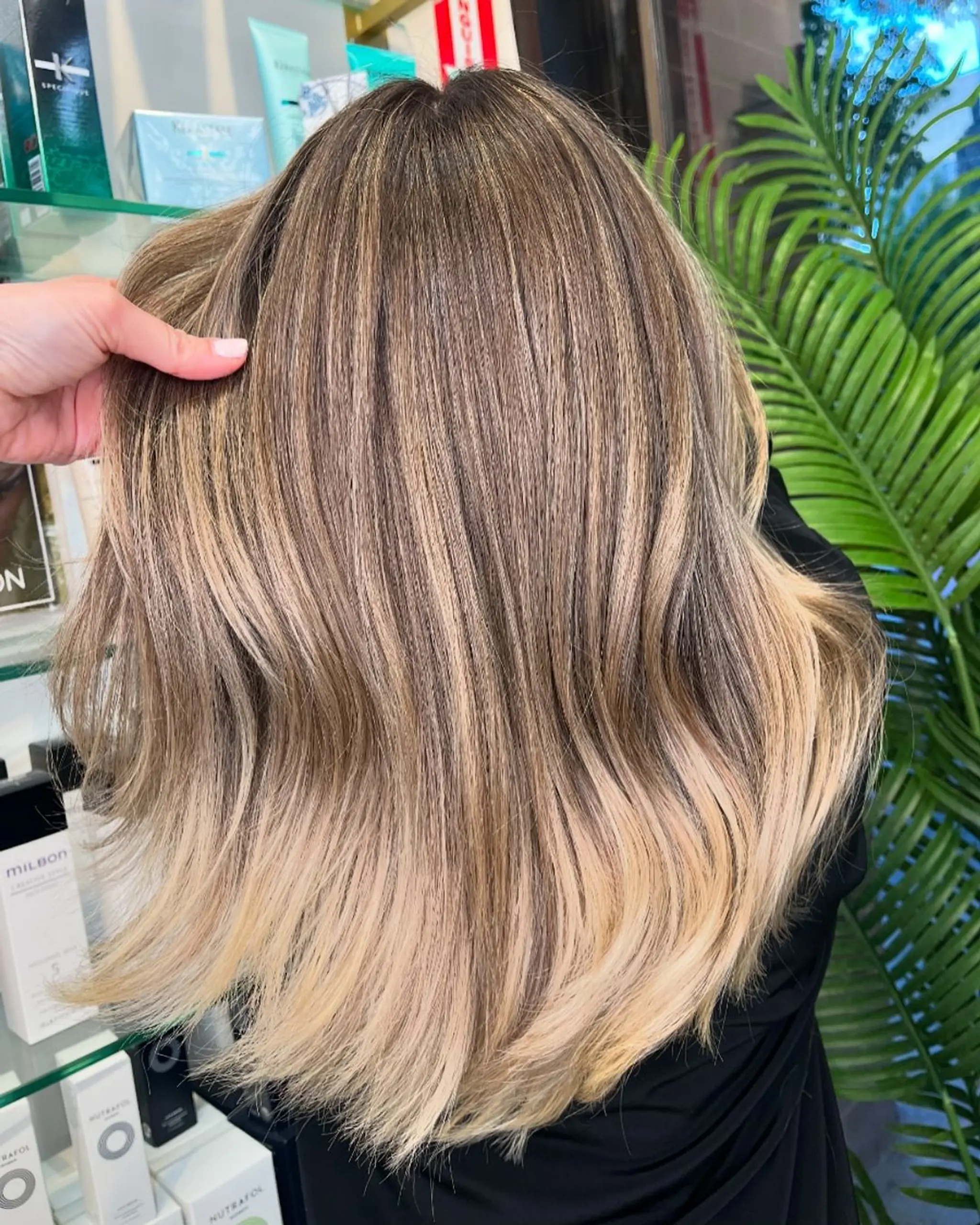 Medium-length, wavy hairstyle with an ombre balayage effect, transitioning from light brown roots to blonde tips.