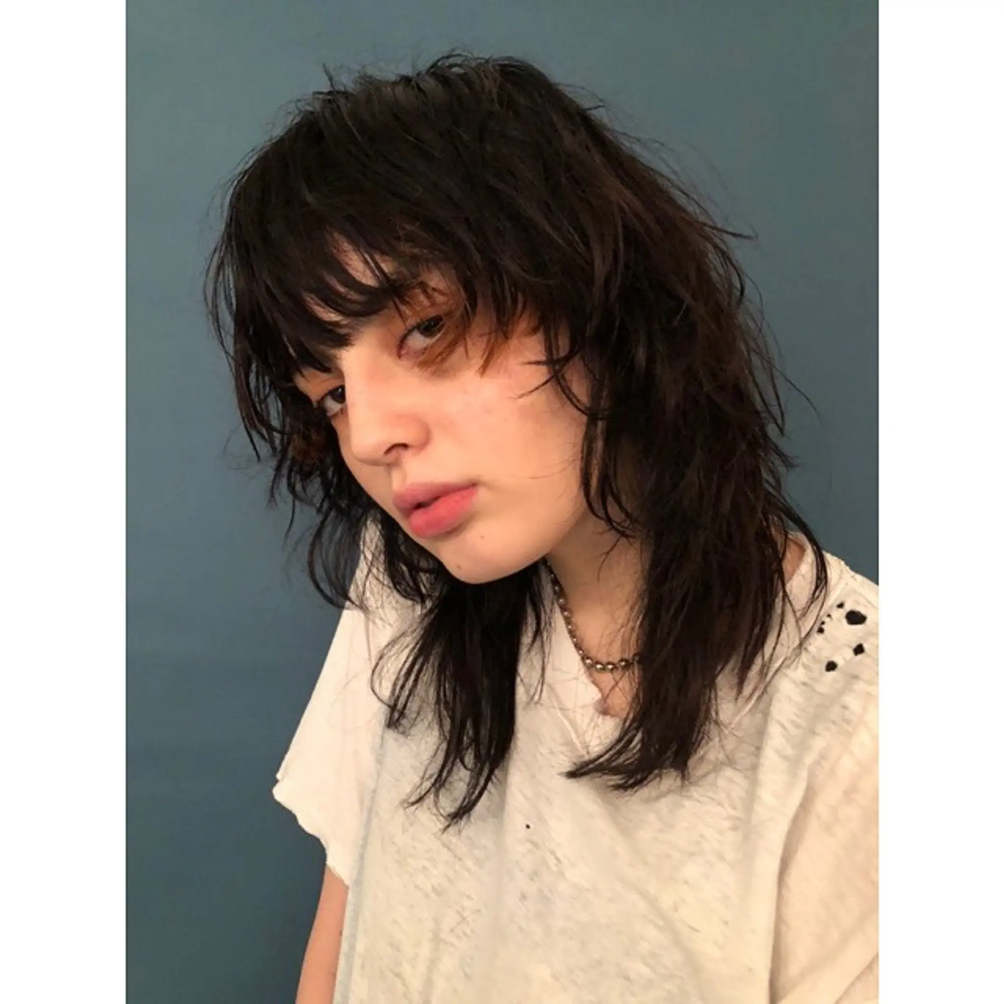 A modern shag haircut with choppy, textured layers and fringe bangs.