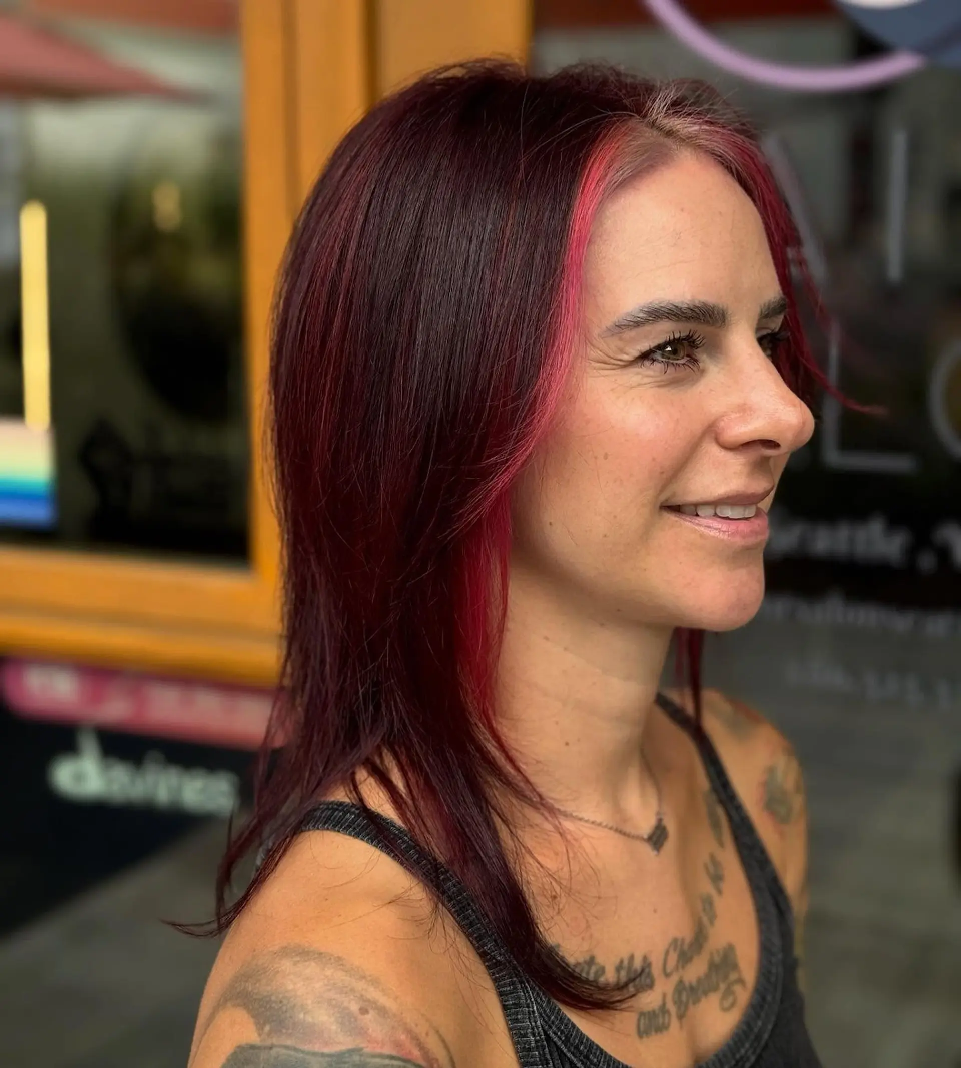 Medium-length straight hair in a dark burgundy shade featuring a vibrant pink face-framing money piece. 1