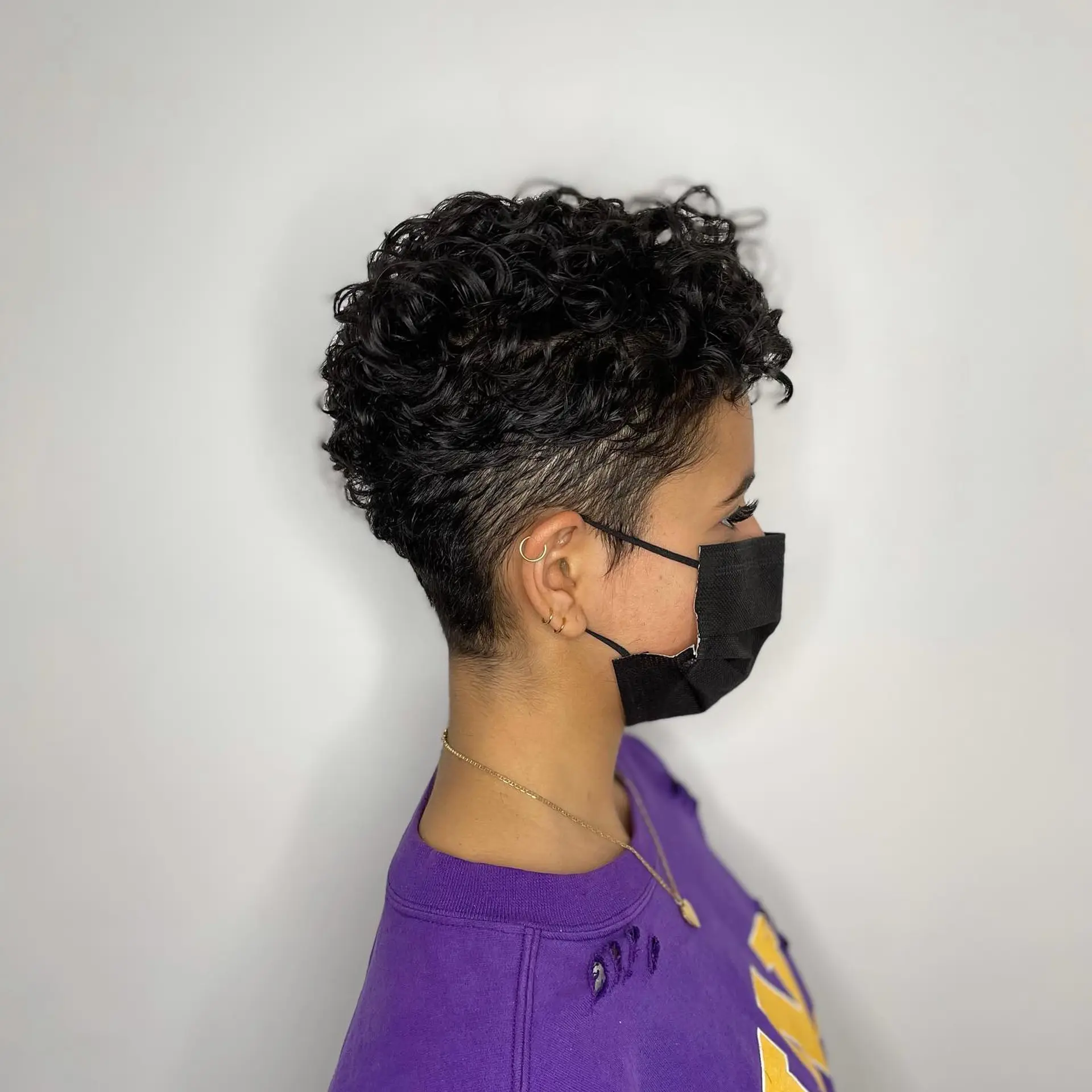A textured curly pixie cut featuring closely faded and tapered sides with defined, voluminous curls on top. 1