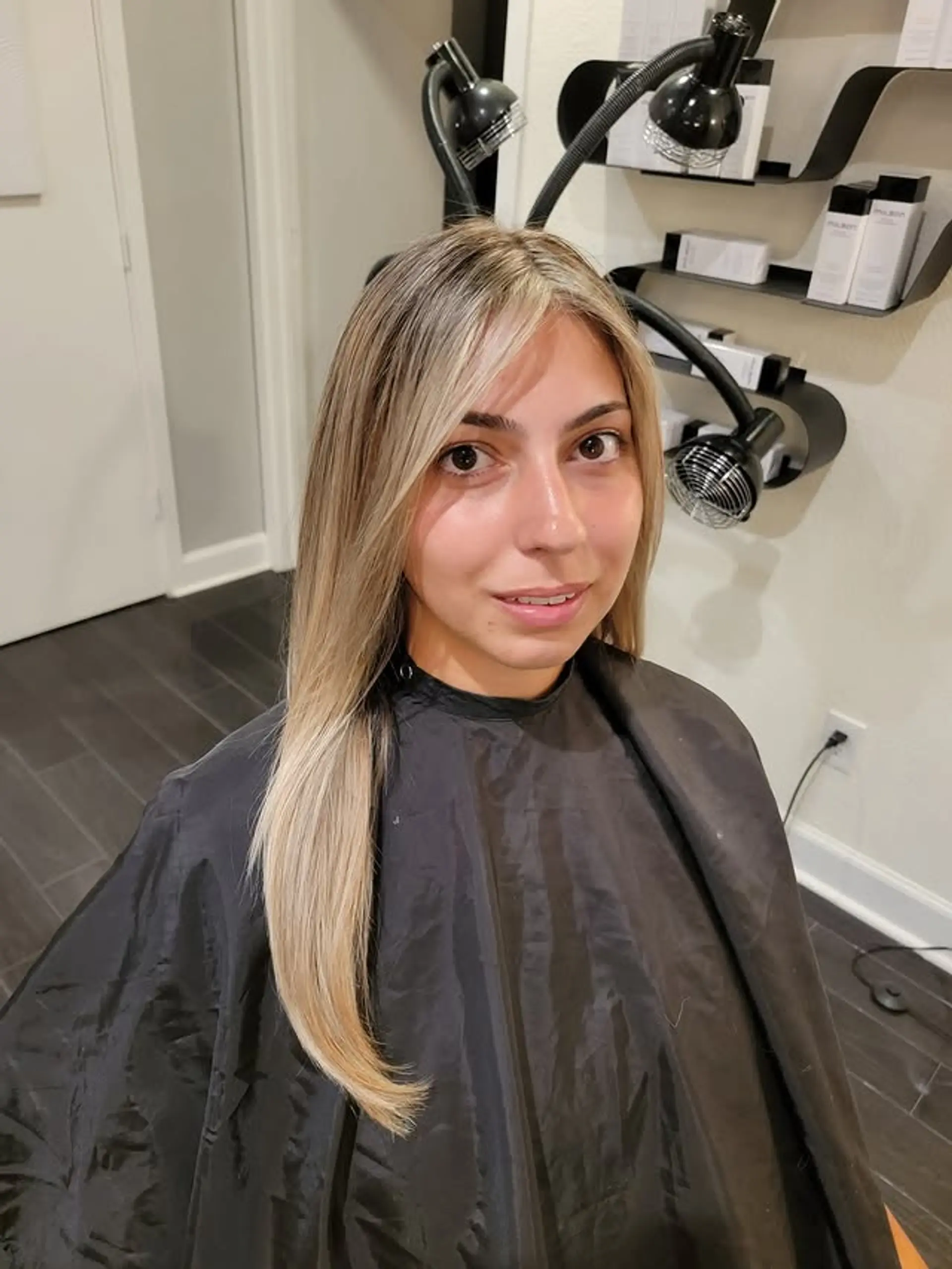 A stunning long, straight hairstyle featuring a seamless ash blonde balayage with natural dark blonde roots and soft face-framing layers for a modern, lived-in look. 1
