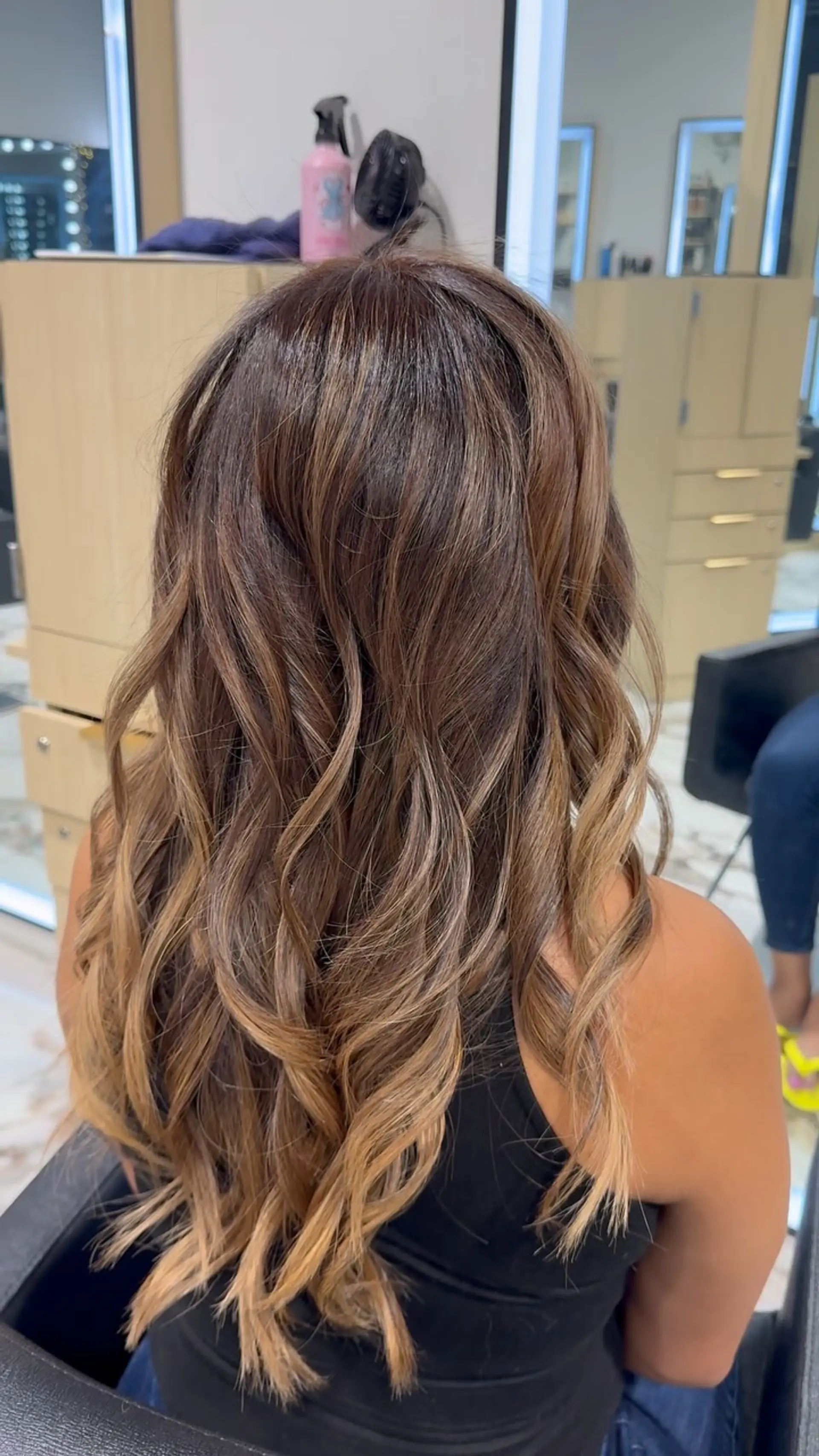 Long dimensional brunette hair styled in loose curls with warm caramel and honey blonde balayage highlights. 1
