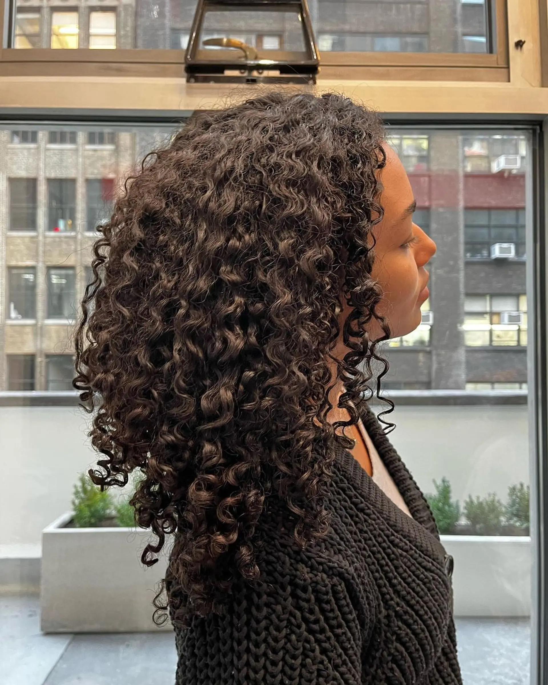 Naturally curly, medium-length black hair with defined and voluminous curls reaching shoulder length, exhibiting healthy shine. 3