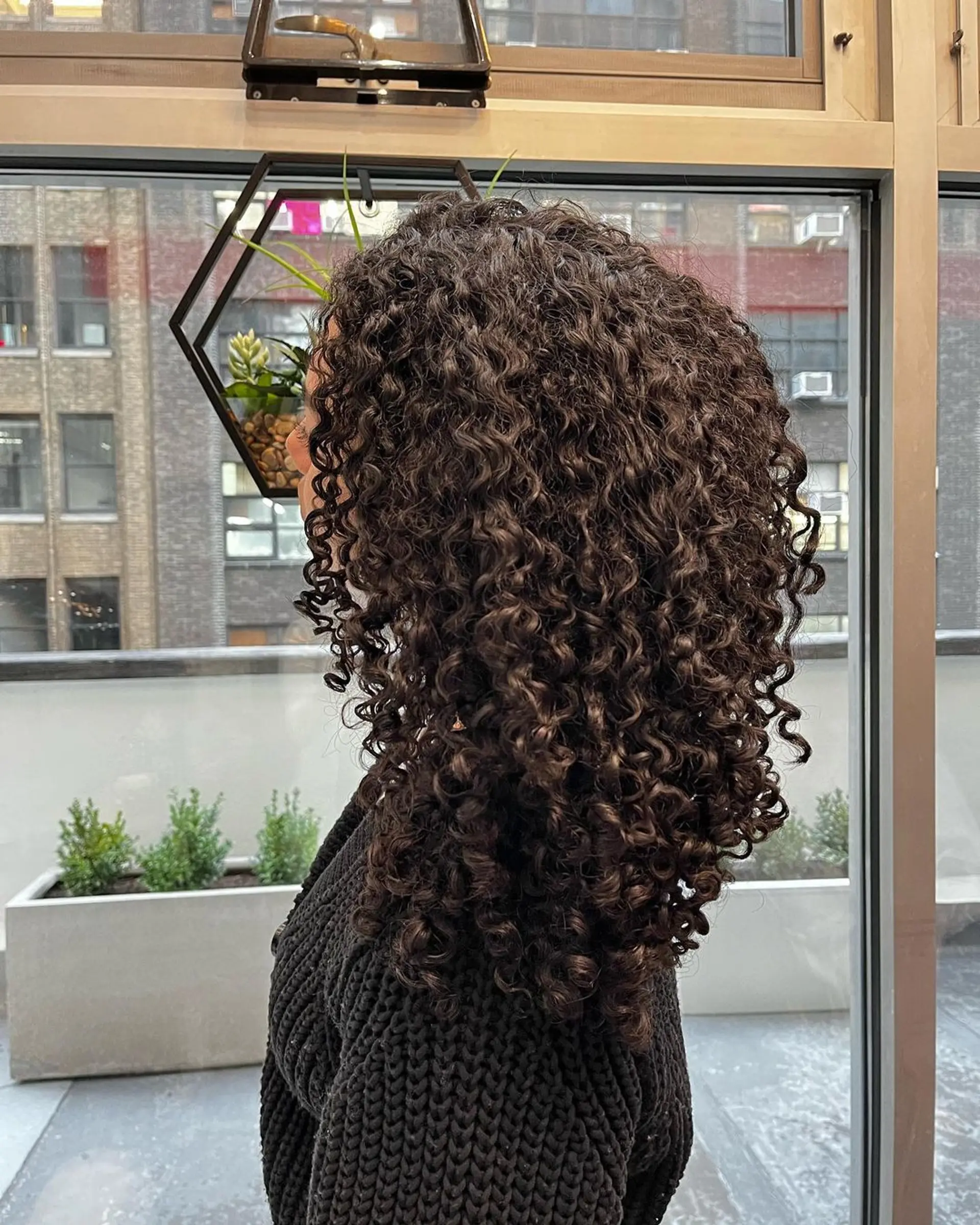 Naturally curly, medium-length black hair with defined and voluminous curls reaching shoulder length, exhibiting healthy shine. 4