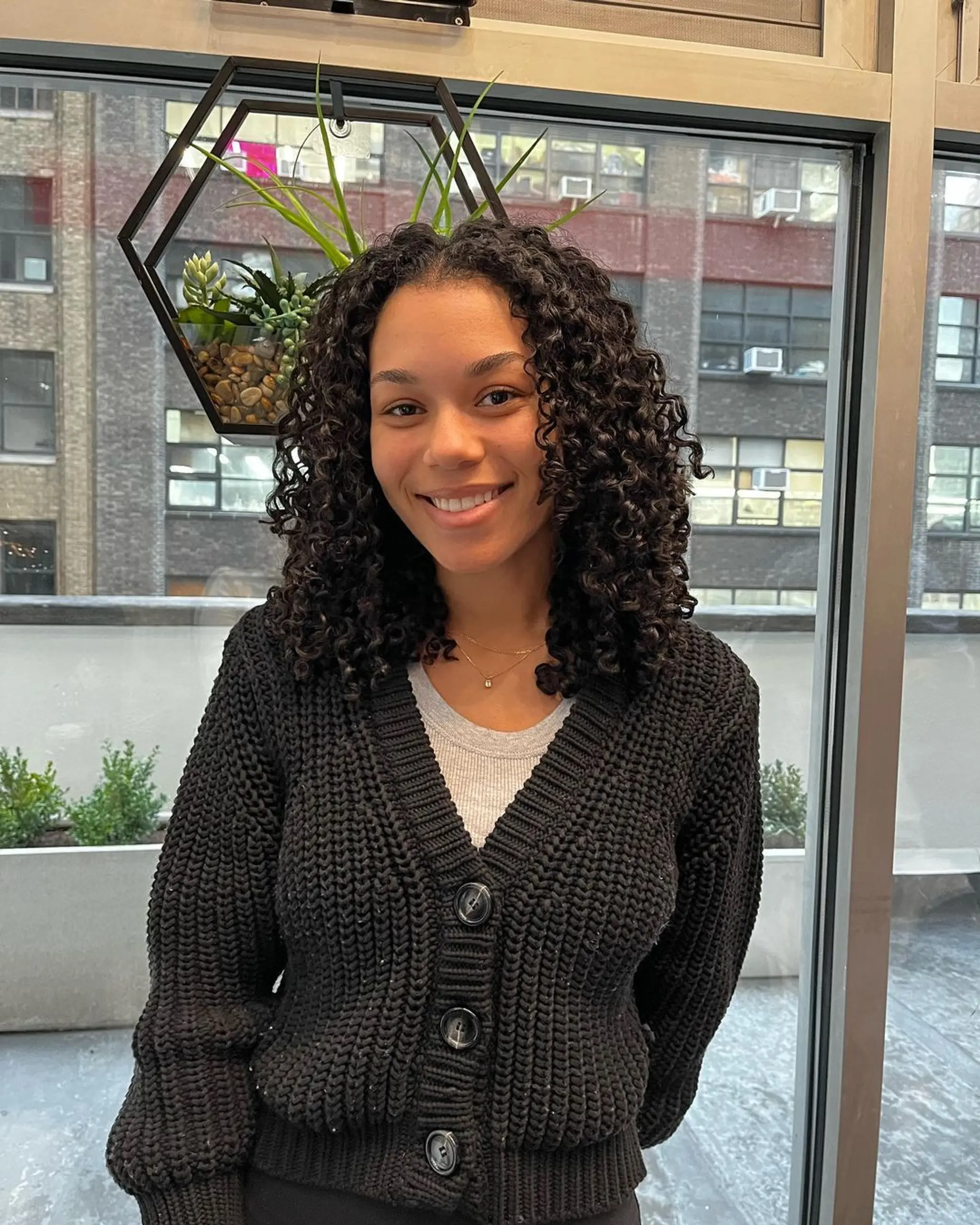 Naturally curly, medium-length black hair with defined and voluminous curls reaching shoulder length, exhibiting healthy shine. 1