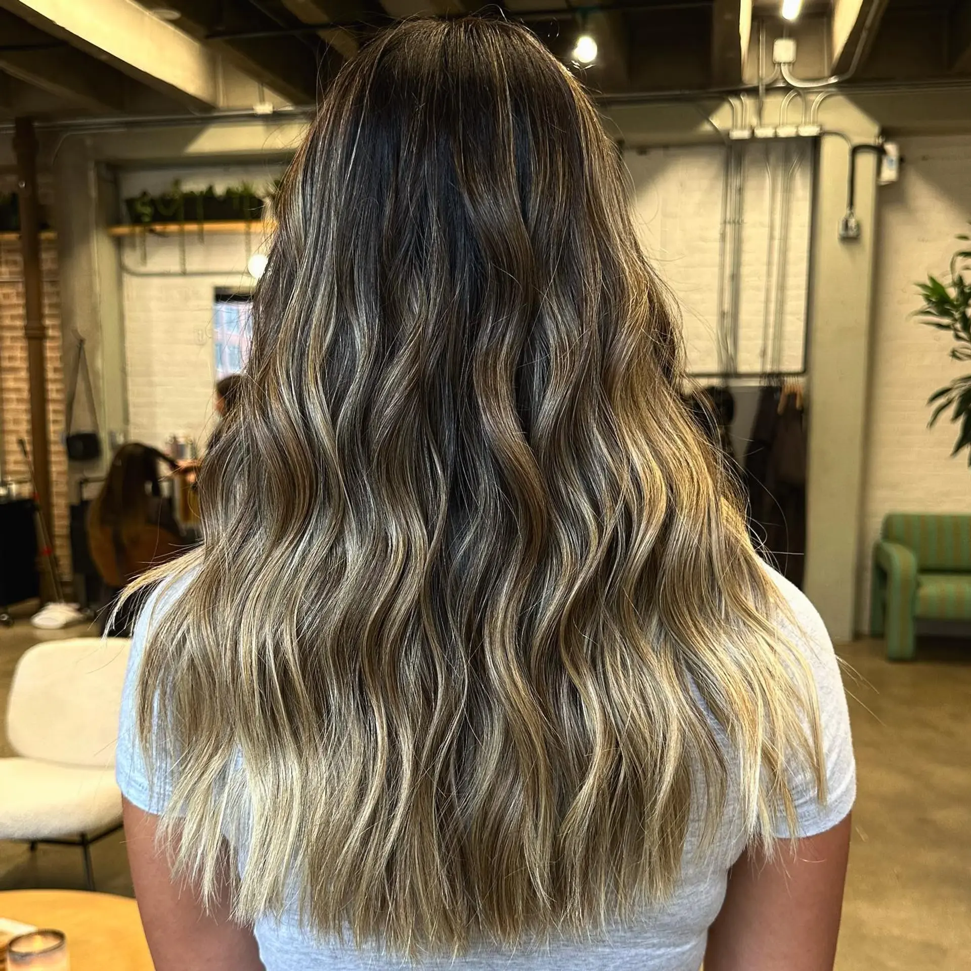 Long layered hair with beachy waves, with a dark brown to blonde balayage. 1