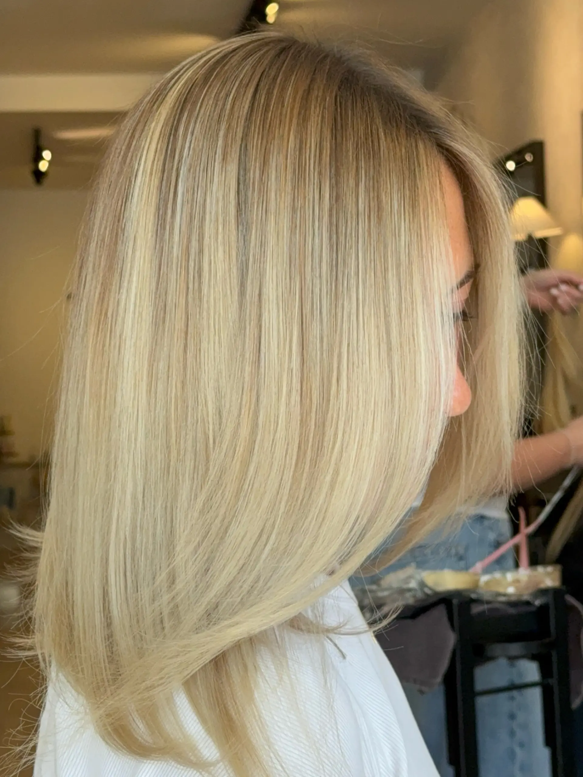 A sleek, smooth medium-length blowout in a bright dimensional blonde shade with natural rooted dimension. 1