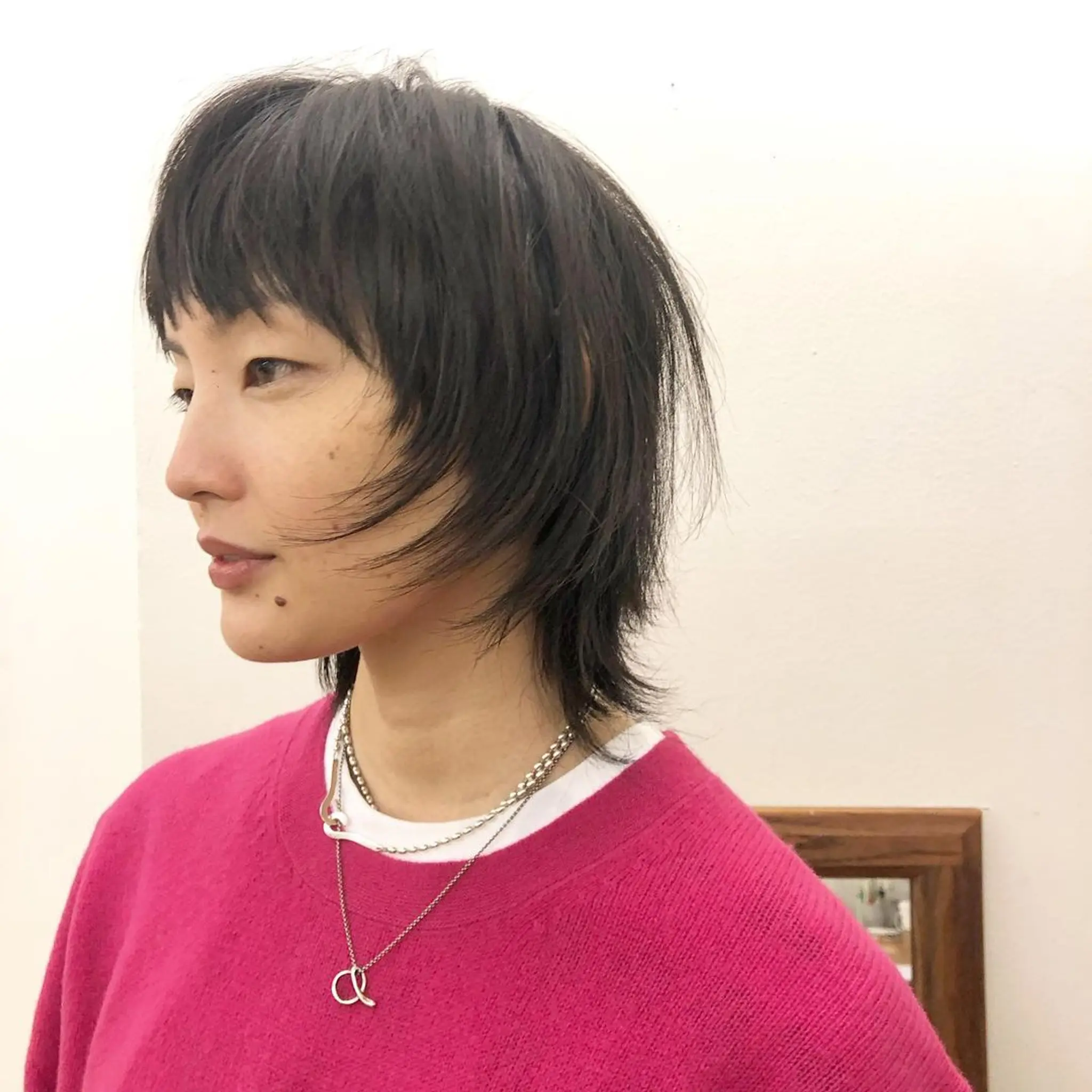 A dynamic and modern shag cut, featuring straight, medium-length hair. The locks are naturally black and exhibit a textured and layered look with a prominent fringe. This edgy style has movement and dimension while maintaining a playful and carefree vibe. by @takeohair