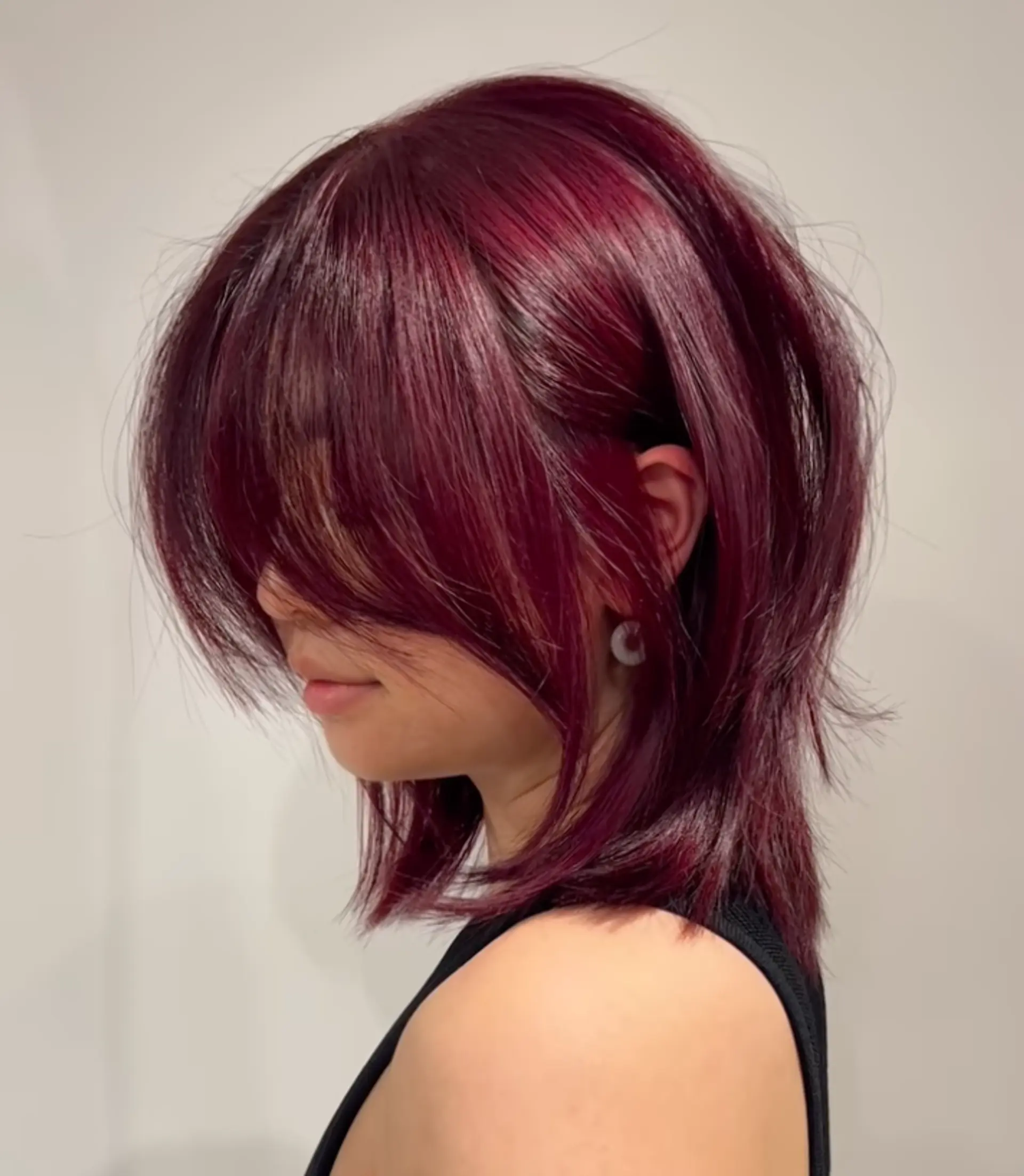 Medium-length, straight hair with feathered layers, side bangs, and choppy ends in a deep burgundy color. 1