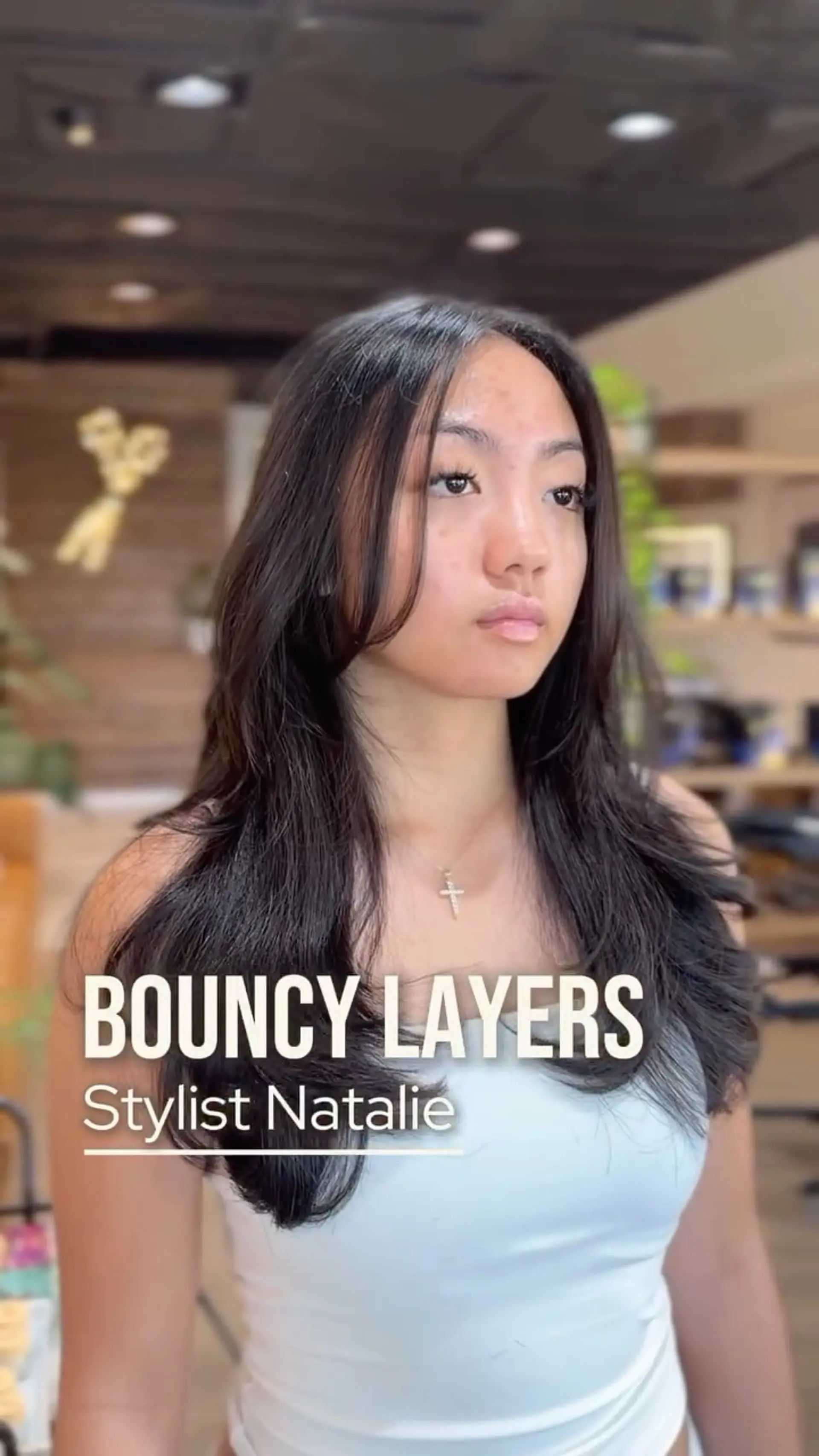 Long dark layered haircut styled with soft face-framing pieces and bouncy, curved ends. 1