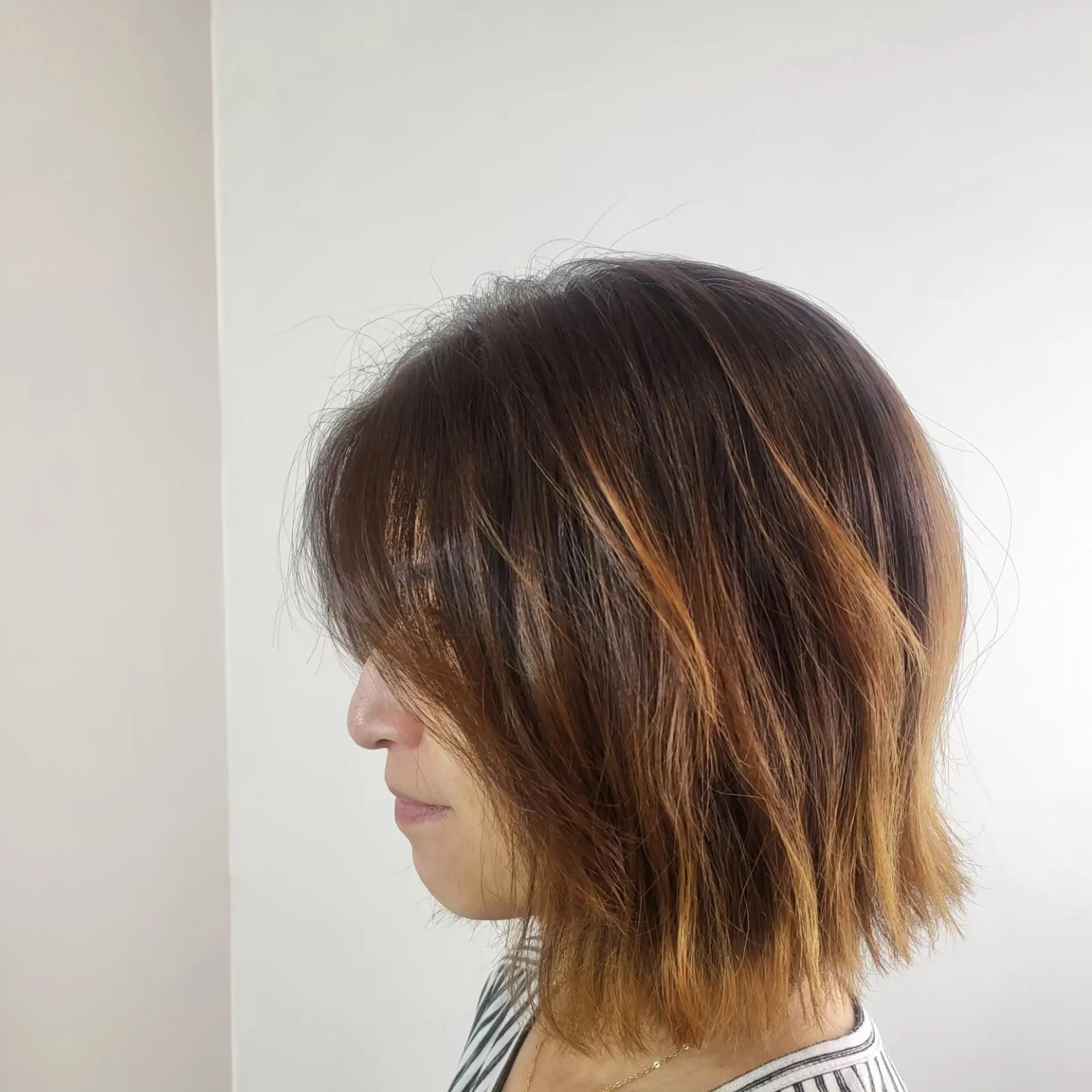 A textured chin-length bob cut paired with soft fringe bangs and warm dimensional highlights. 1