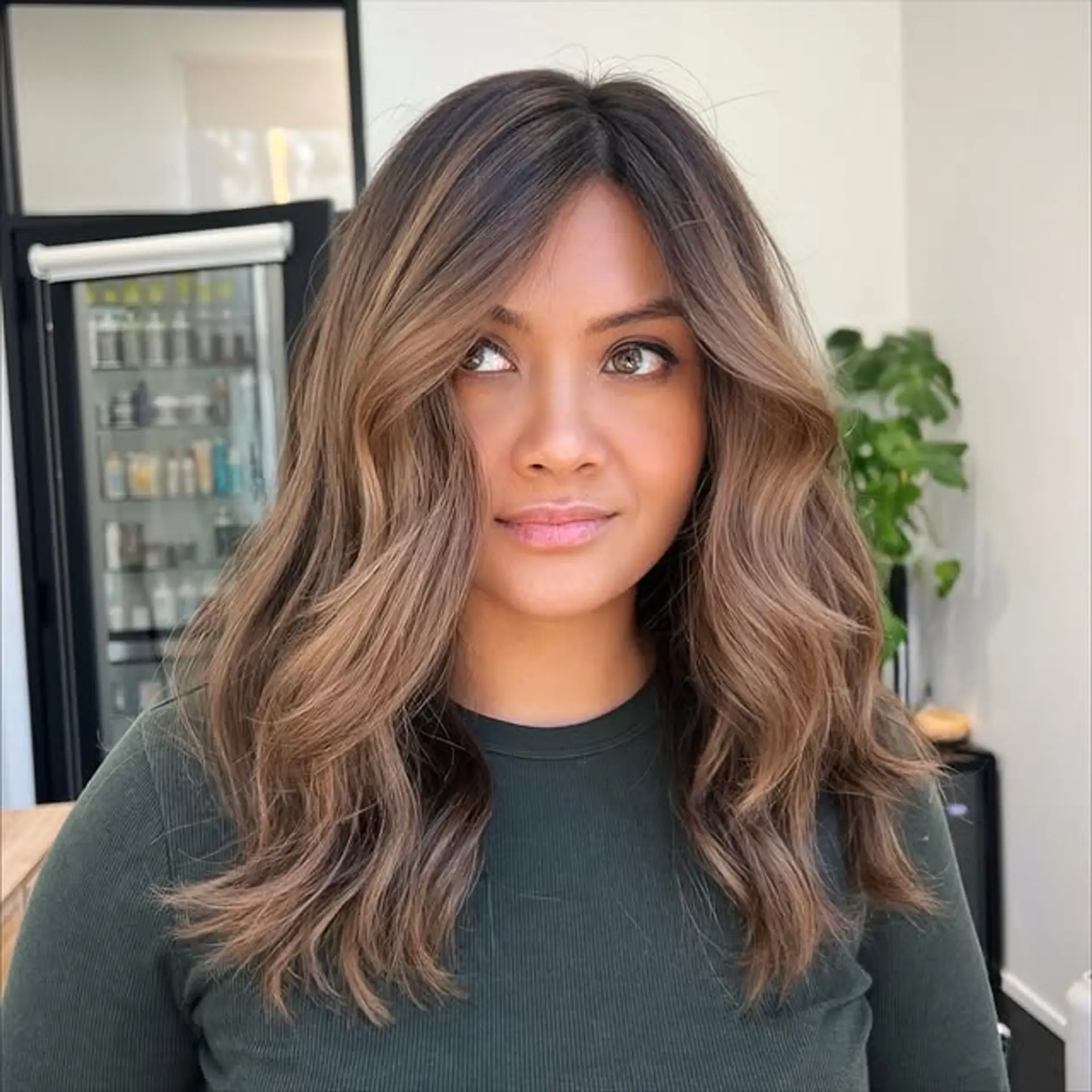 A wavy medium-length hairstyle with a bronzed balayage and face-framing layers. 1