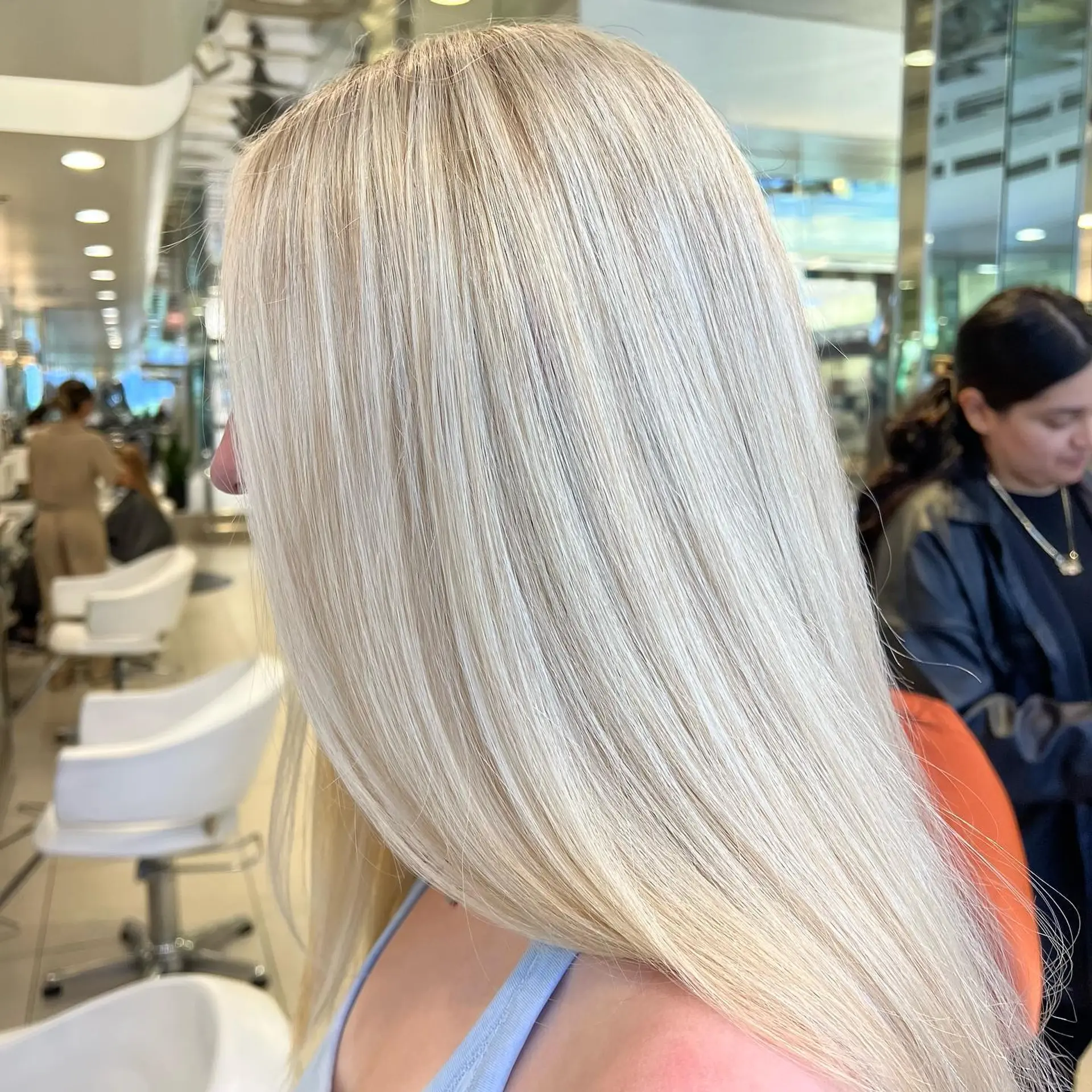 Long, pin-straight platinum blonde hair styled with a sleek, high-shine blowout. 1