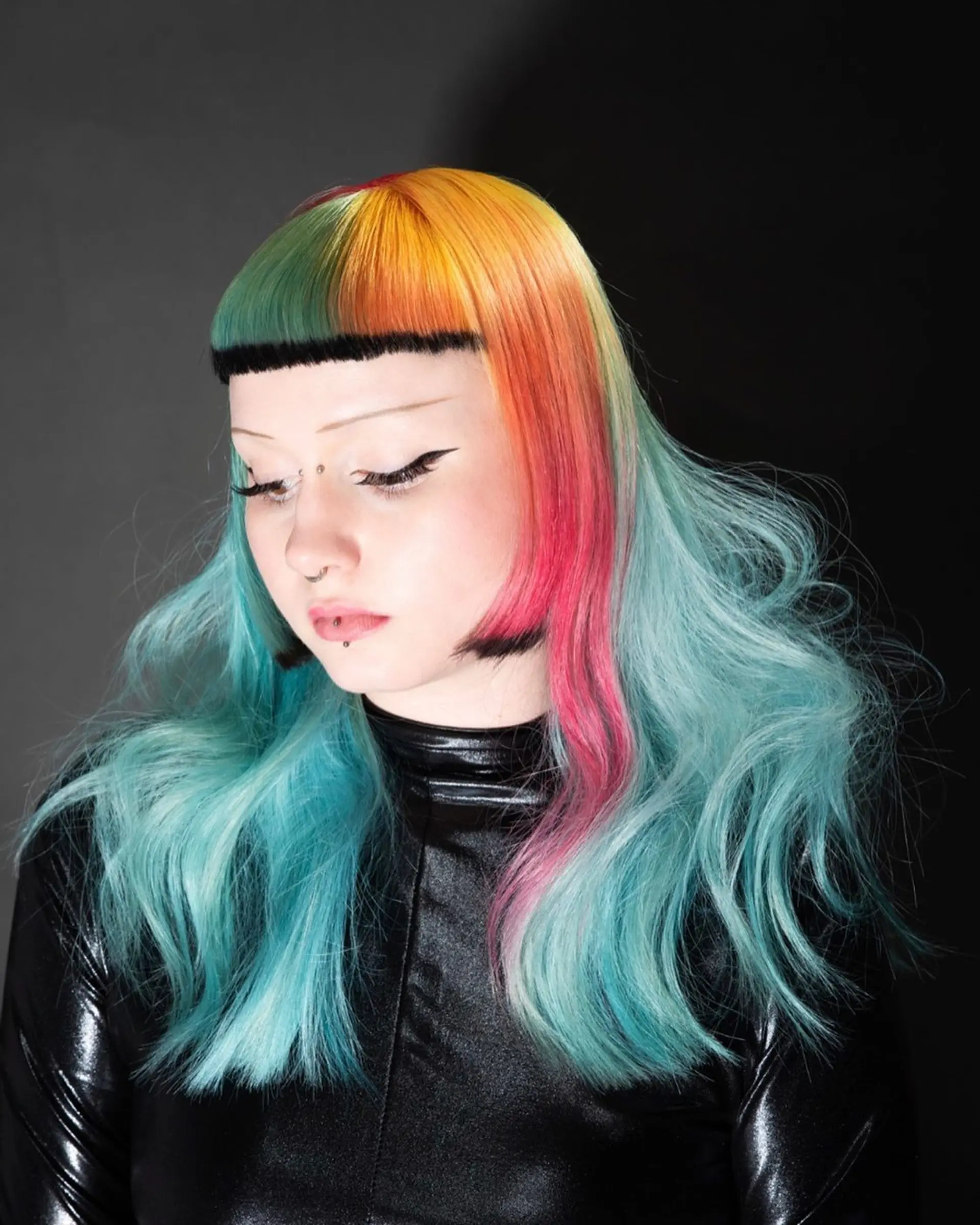 A bold alternative cut featuring blunt micro bangs, cheek-length face-framing sections, and vibrant multi-colored panels over pastel aqua lengths. 1
