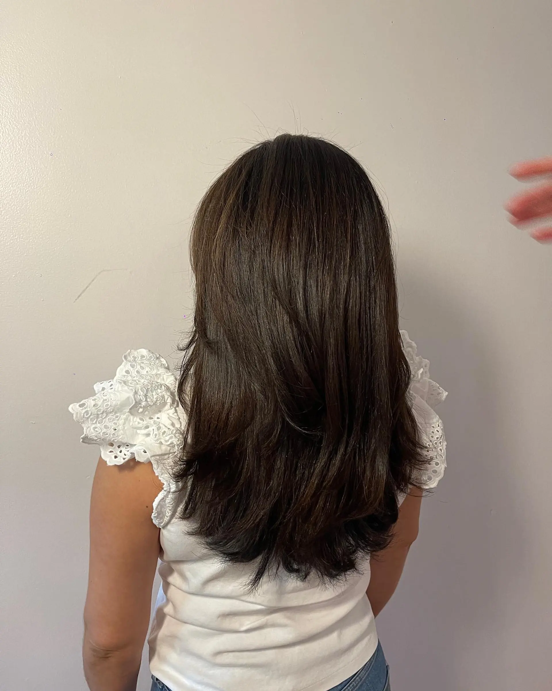 Long rich dark brown hair cut with soft cascading layers and curved ends. 1