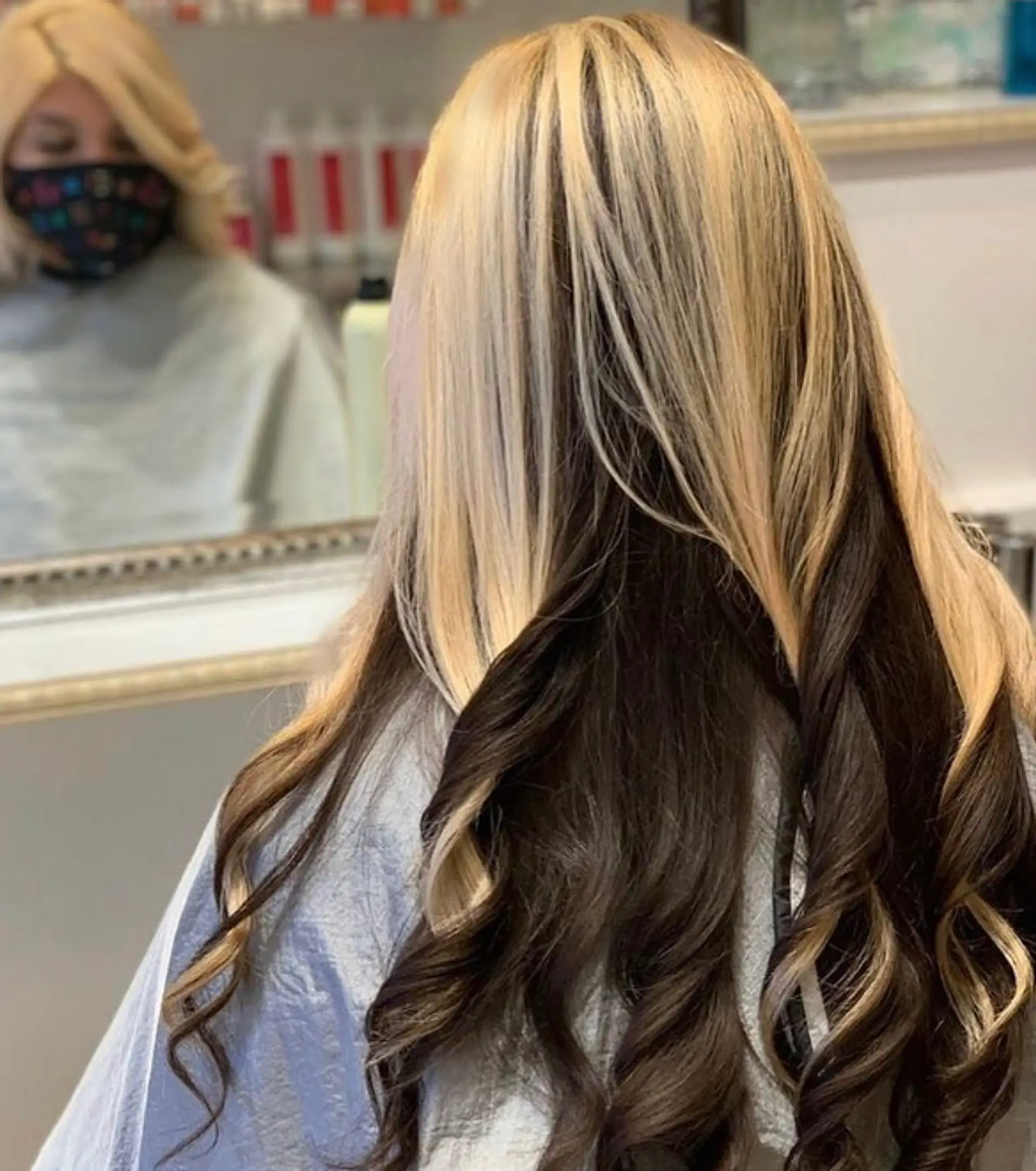 Long wavy hair with a striking two-toned color effect, featuring blonde on top and brunette underneath. 1