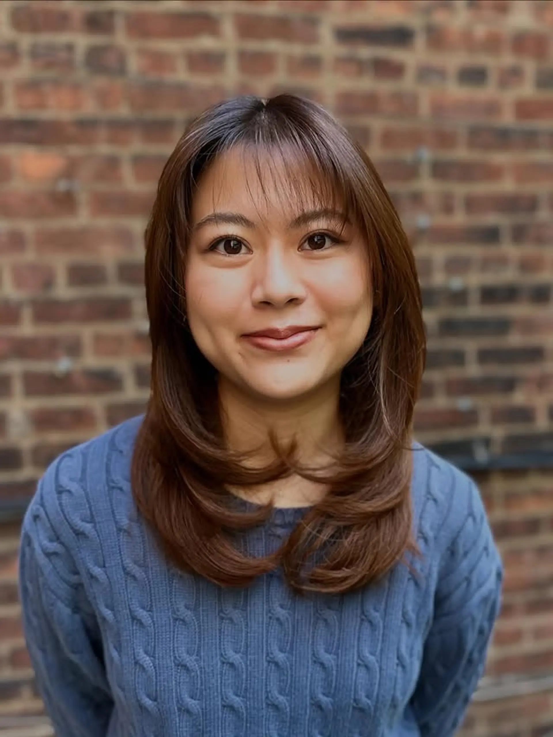 A layered medium hairstyle with face-framing curtain bangs. 1