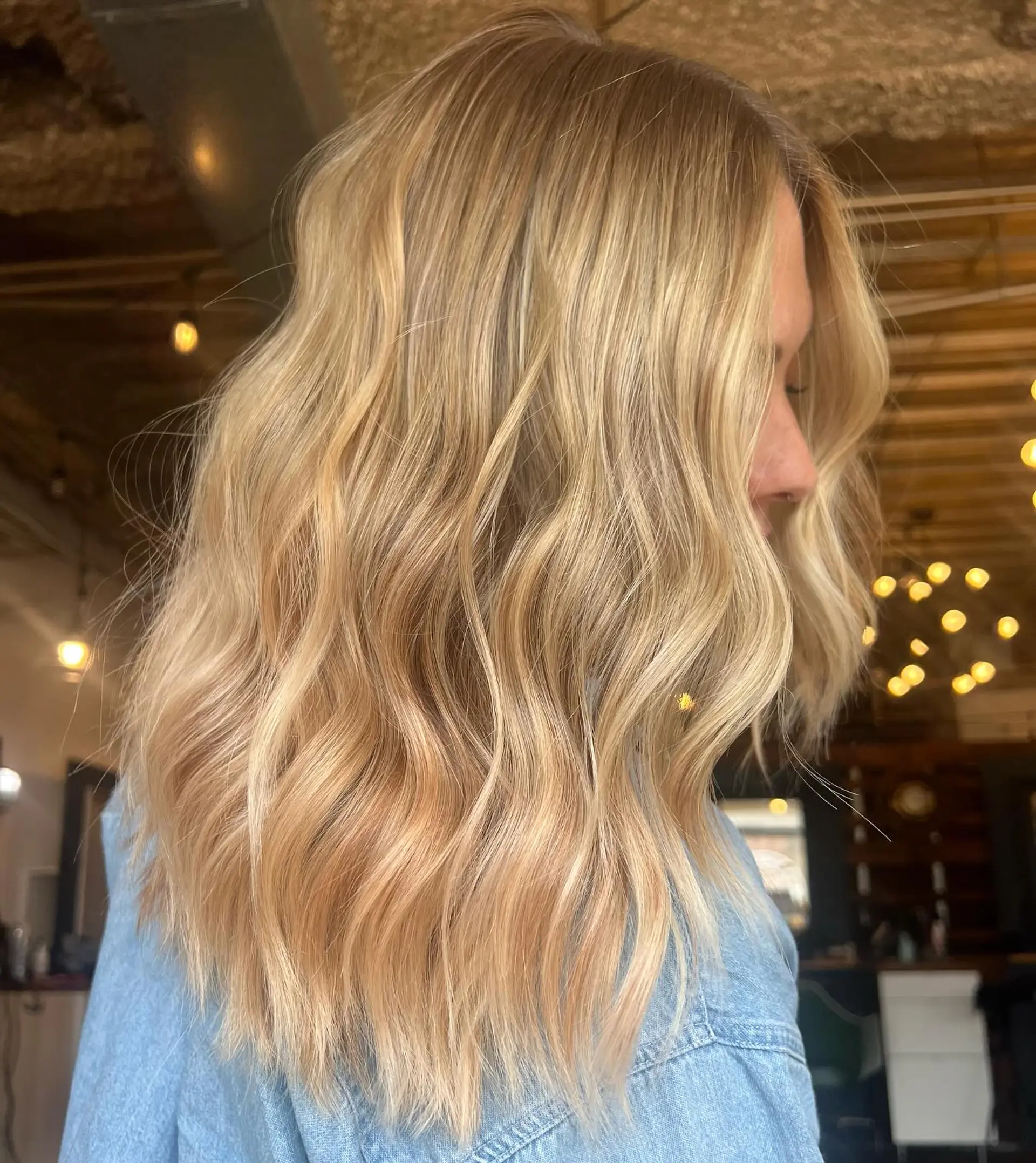 Medium-length dimensional warm blonde hair styled in effortless, soft textured waves. 1